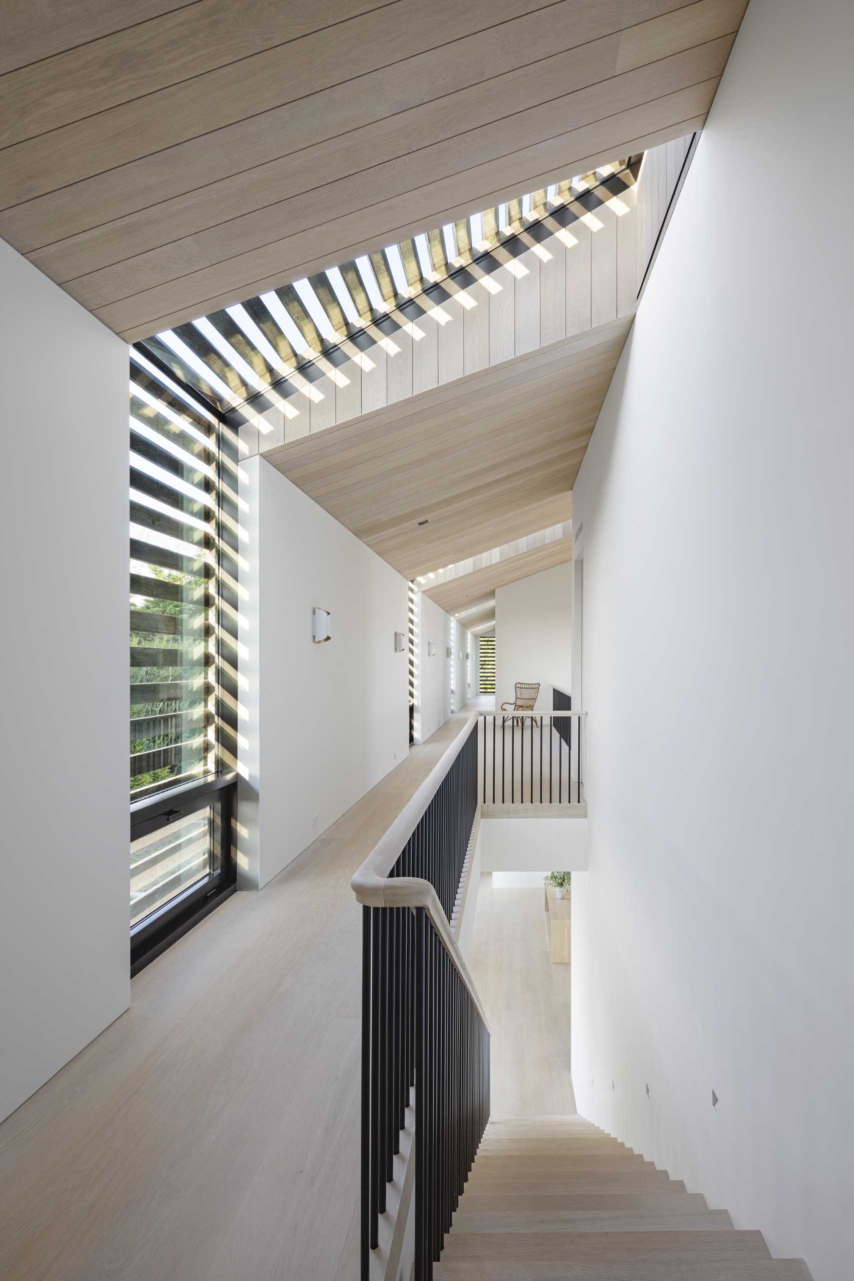 A modern staircase that has a window that wraps from the wall to the ceiling.