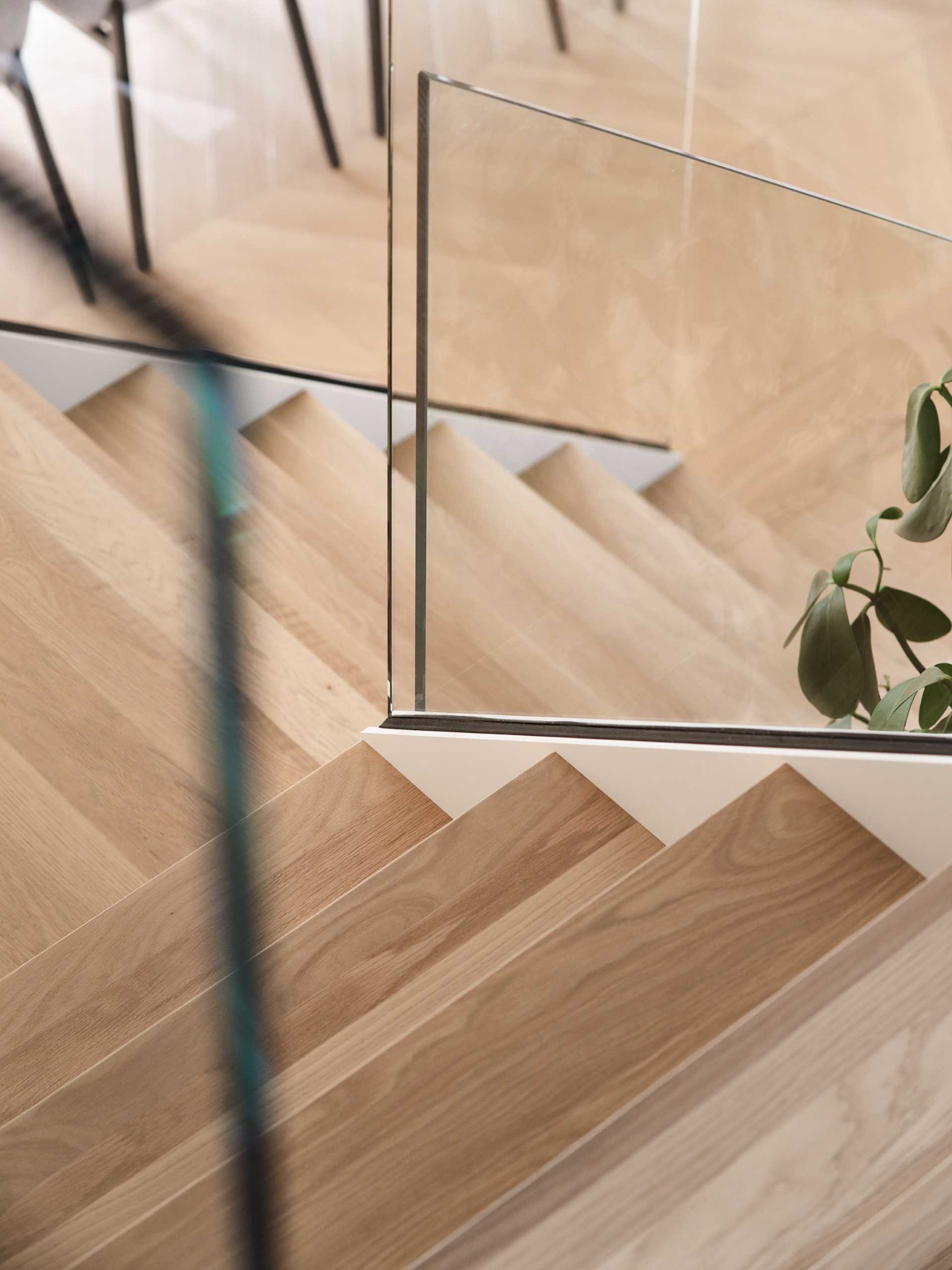 Stairs with wood treads and glass railings lead from the dining area up to the more private spaces of the home.