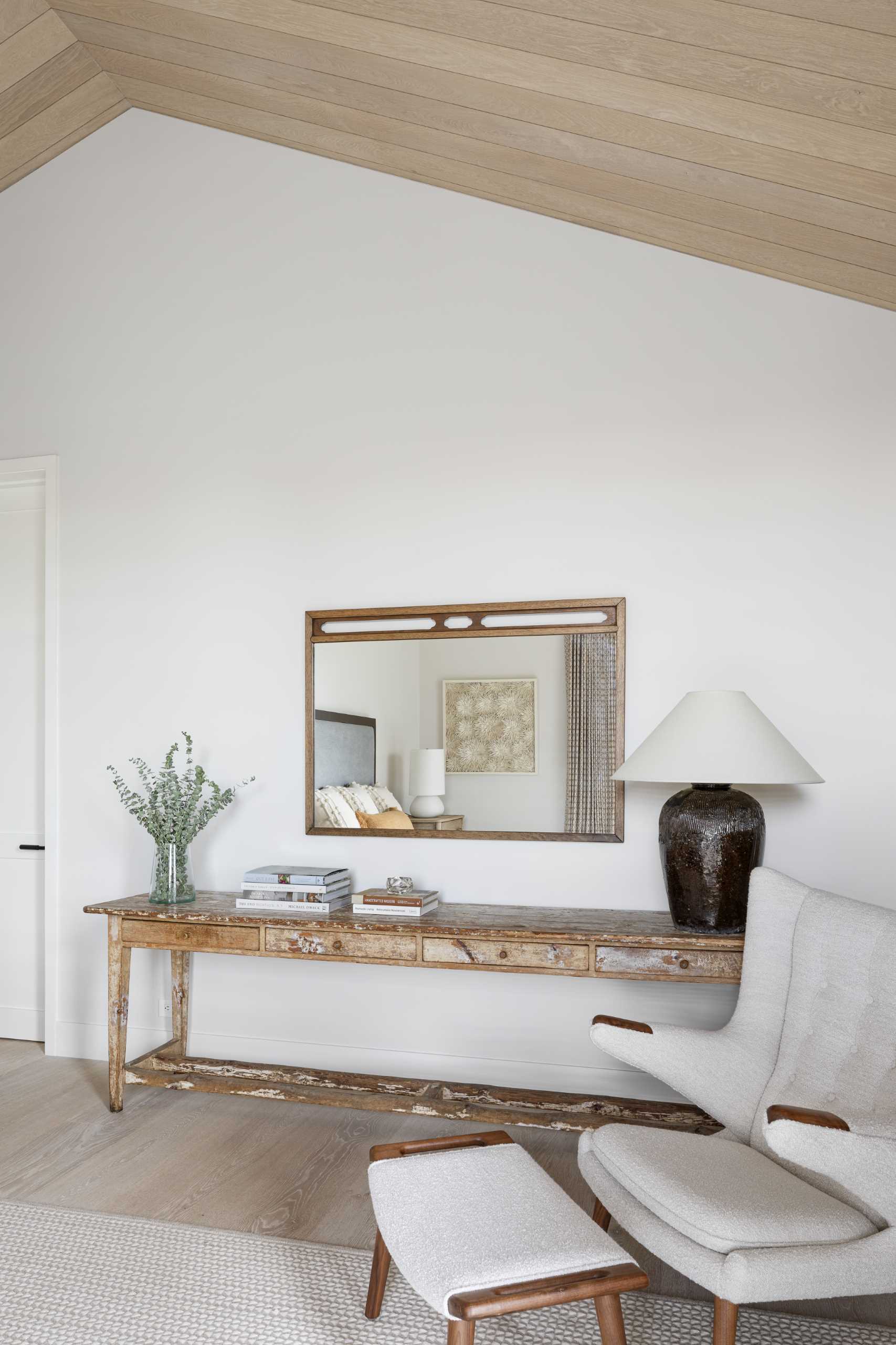 The primary bedroom has a wood ceiling and windows that provide views of the trees.