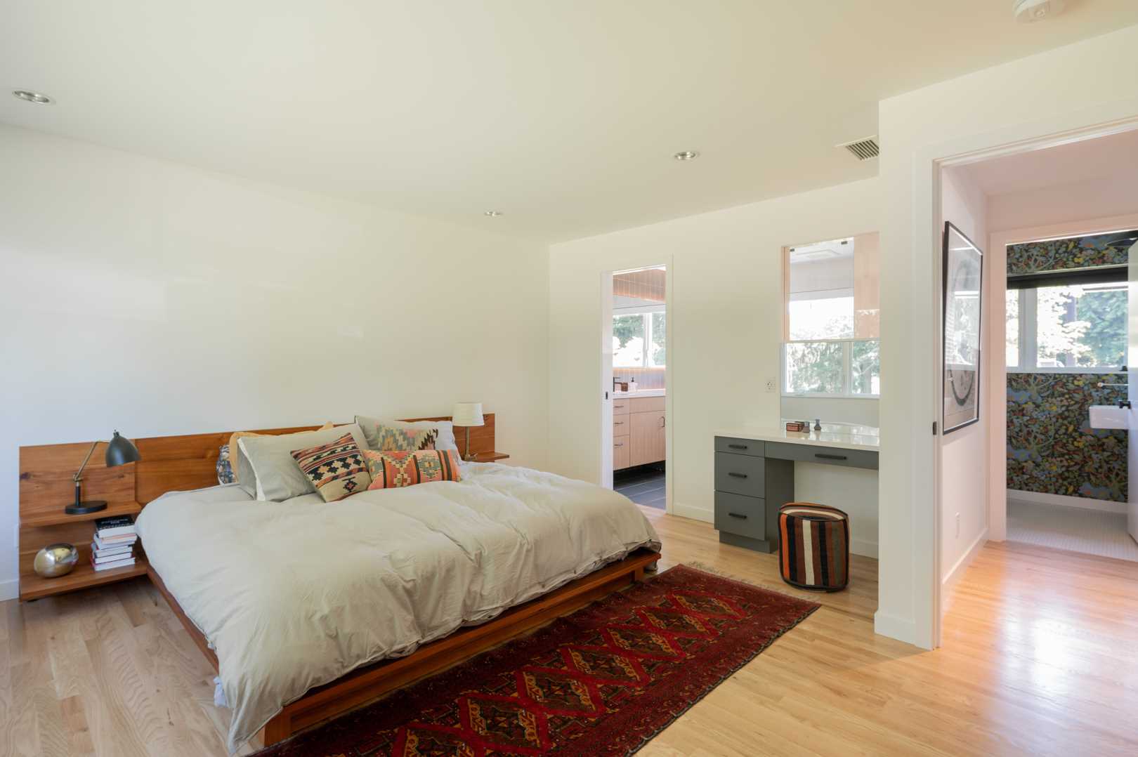 At the end of the hallway is the primary bedroom which has been minimally furnished with a wood bed frame.