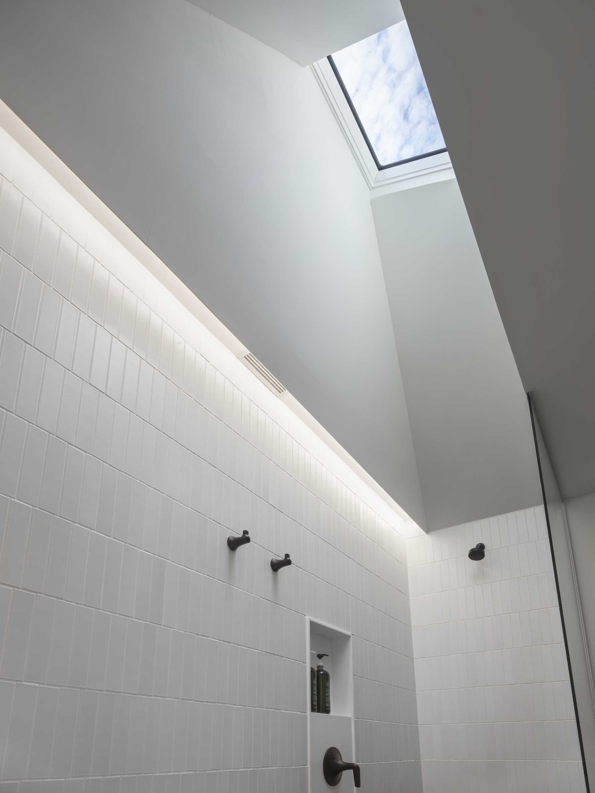 The primary bathroom has a hexagonal tile floor and a skylit wet zone containing the shower and tub.