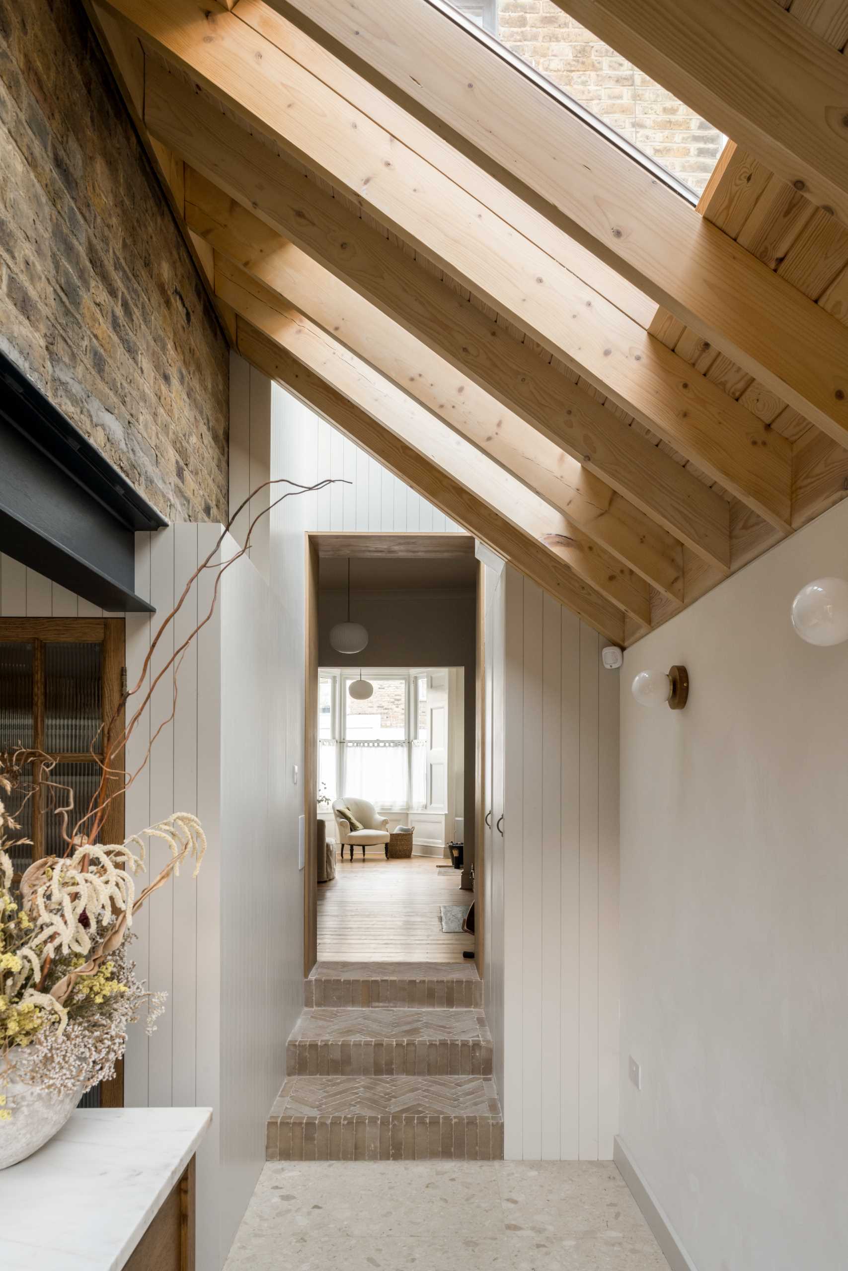 Windows between angled pine joists fill the hallway that connects the new extension to the original home with natural light.