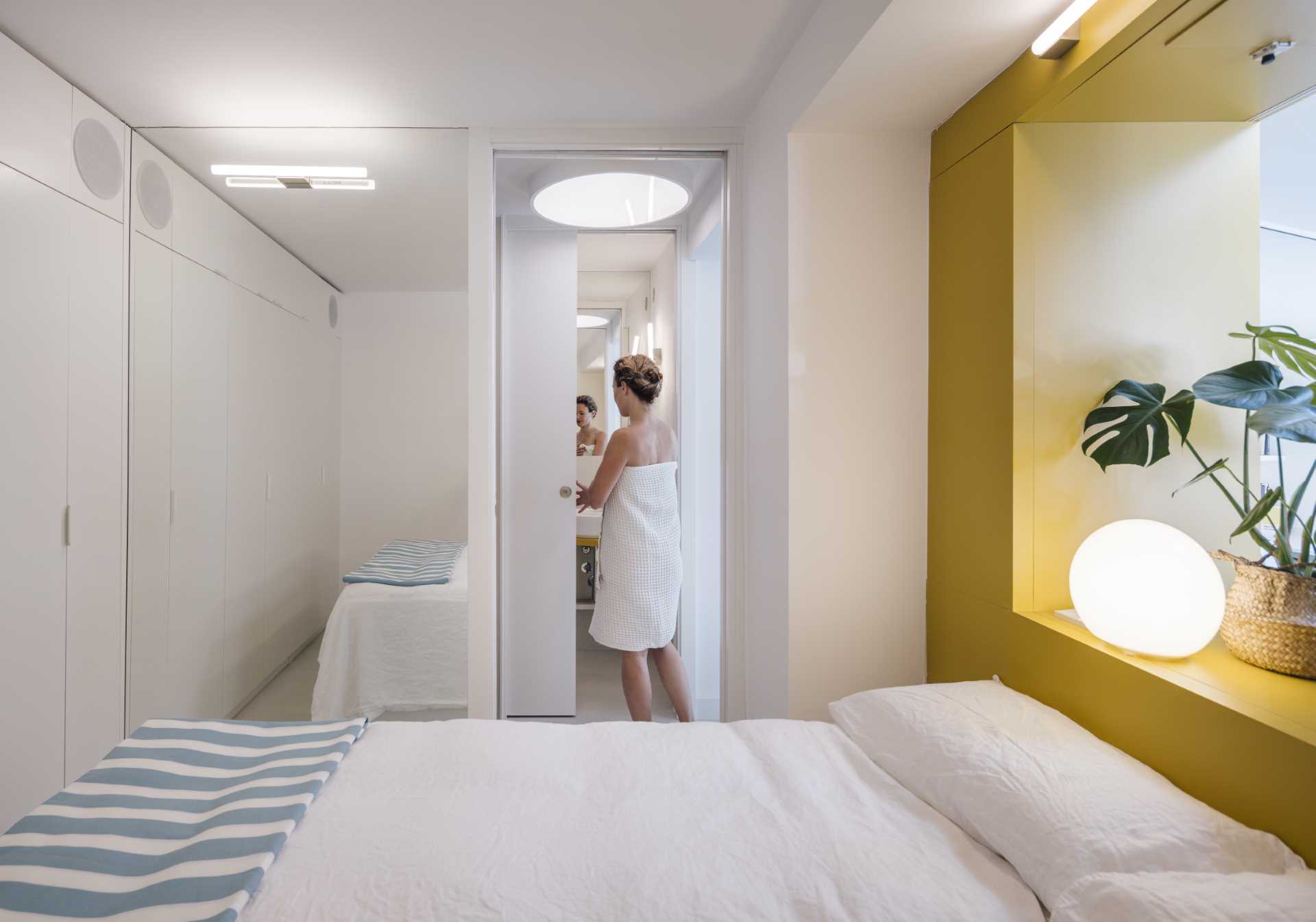 The bedroom of a small apartment includes a floor-to-ceiling mirror that makes the room feel larger.