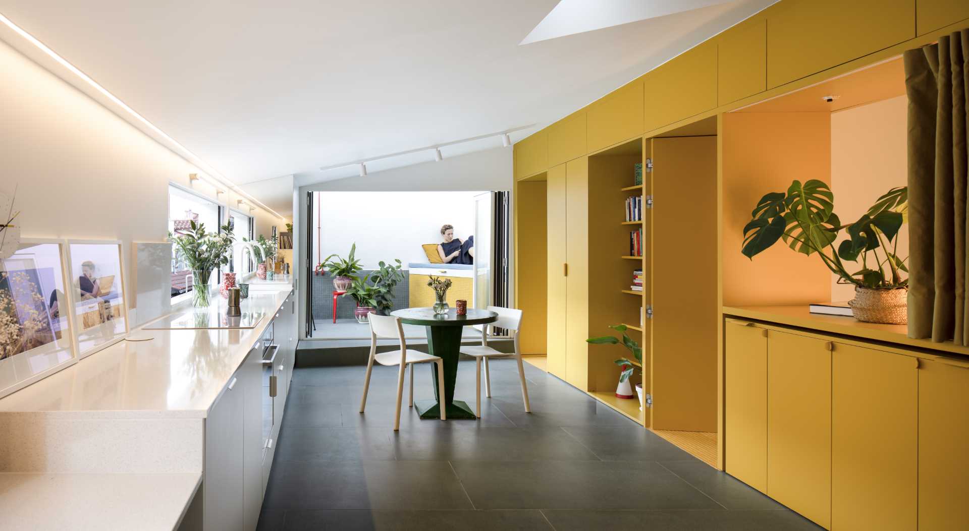 A small apartment with a yellow accent wall that includes plenty of storage and hides the bedroom and bathroom.