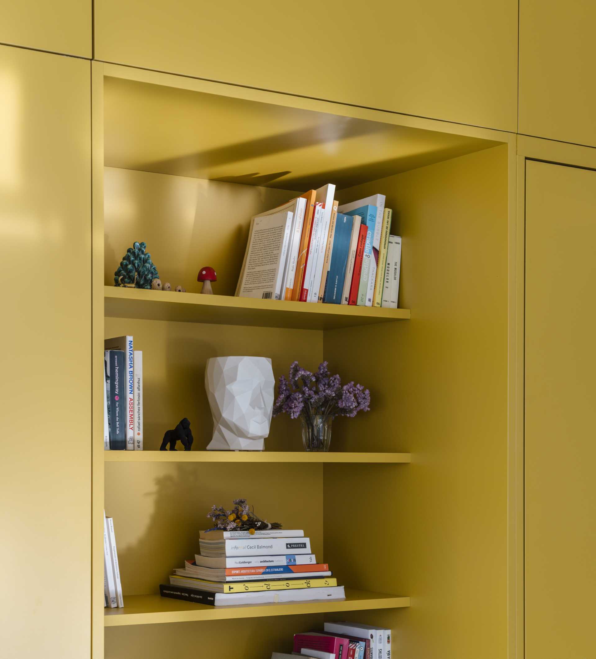 A small apartment with a yellow accent wall that includes plenty of storage and hides the bedroom and bathroom.