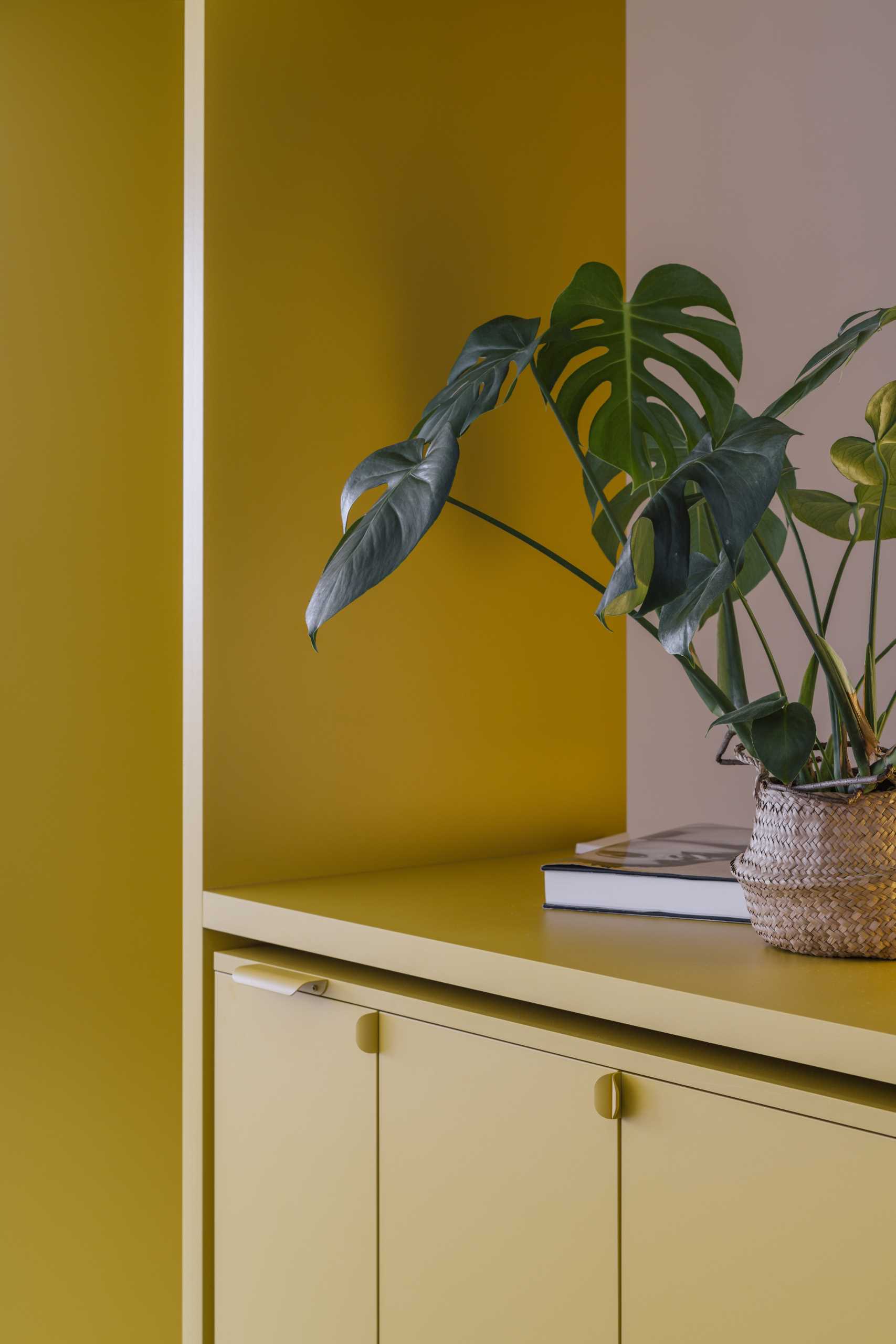 A small apartment with a yellow accent wall that includes plenty of storage and hides the bedroom and bathroom.