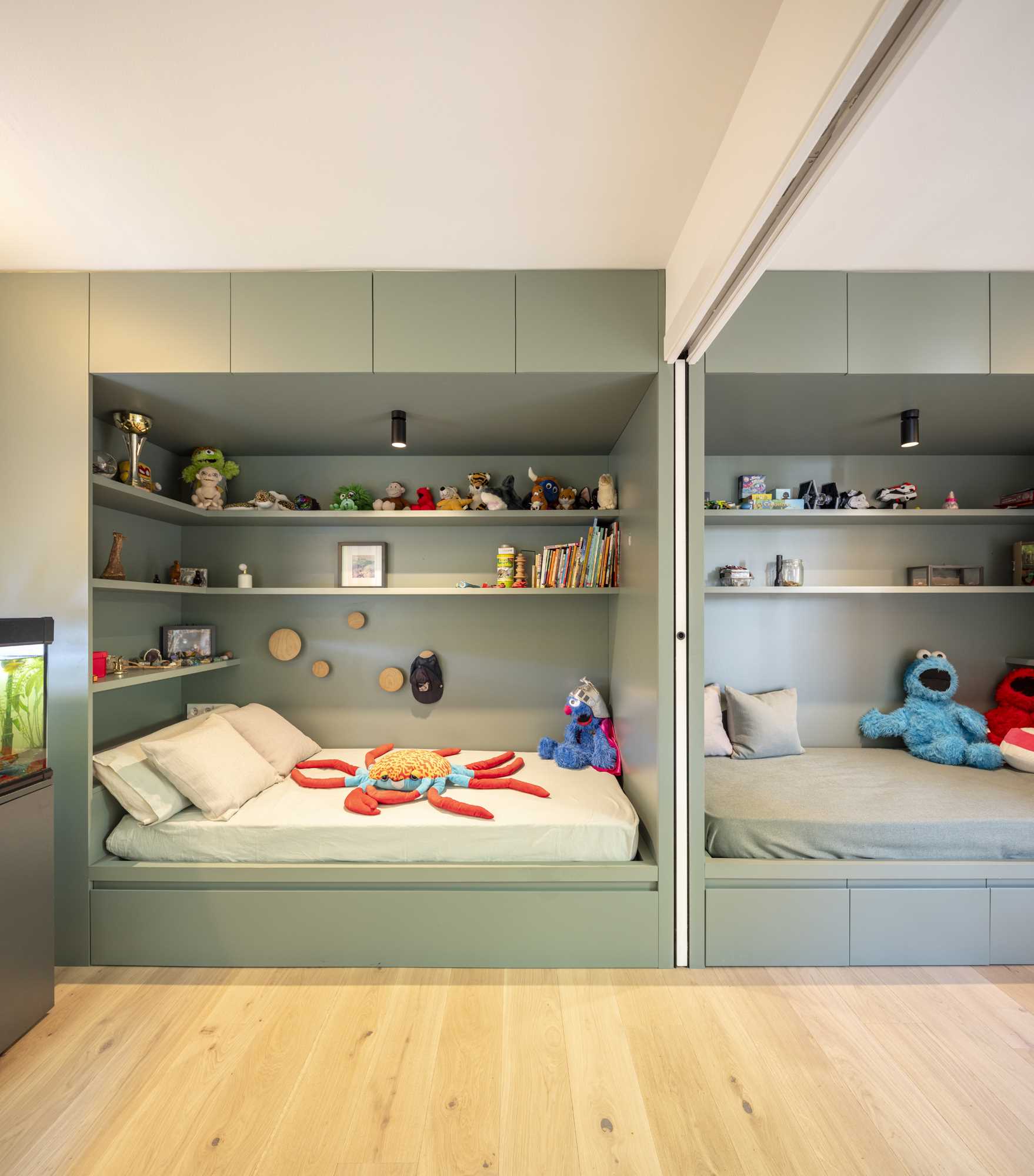 Two kids bedrooms, each with a built-in bed and storage, are connected by sliding doors.