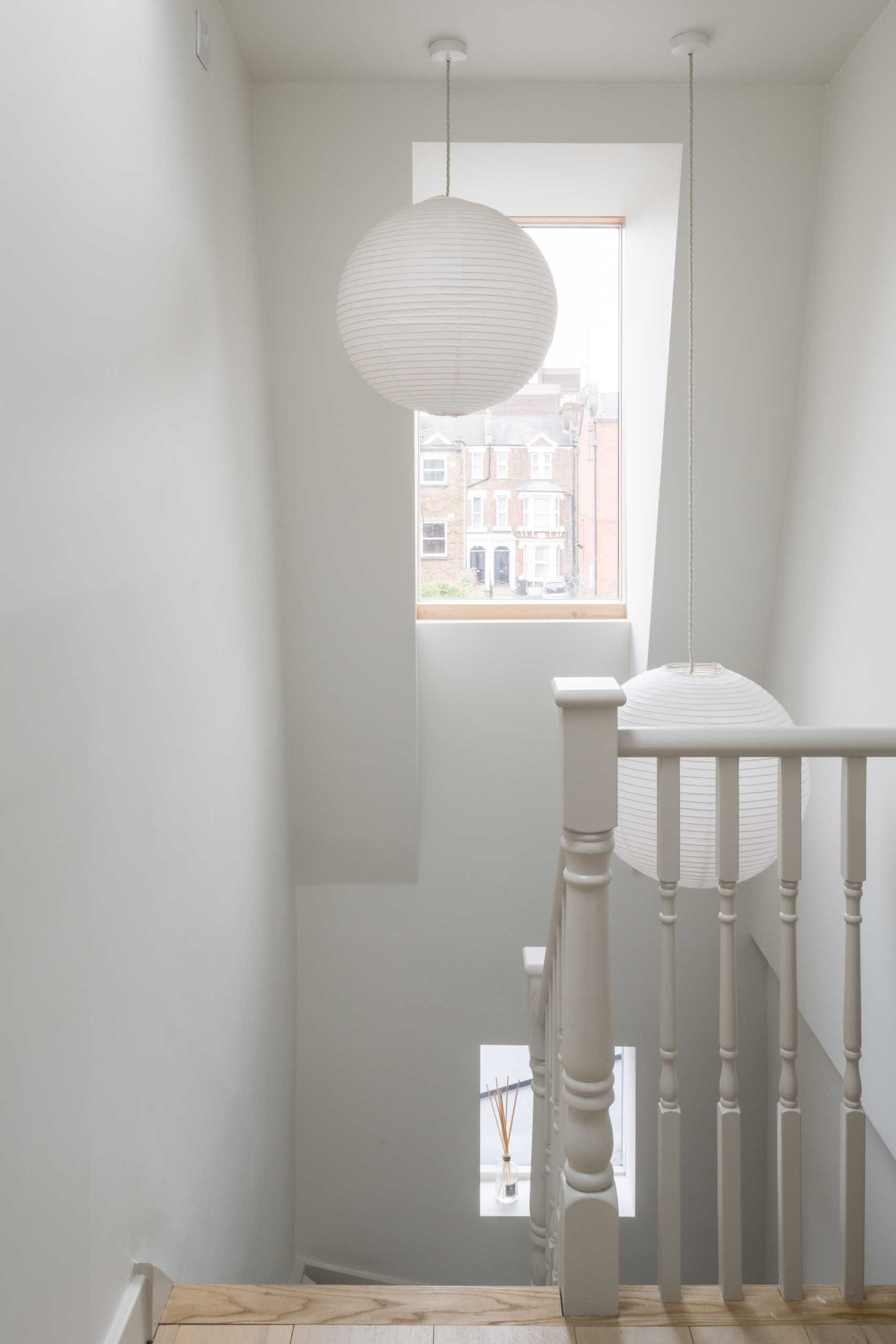 Stairs from the main living level of the home lead up to a loft that's home to the primary bedroom suite, while a tall window provides natural light.