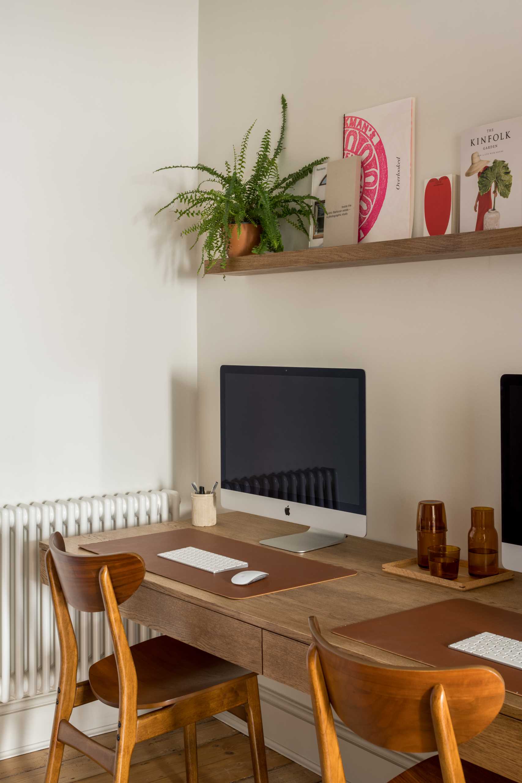 A work area is positioned in a room between the kitchen and the front living room, with a wood desk that's for two.