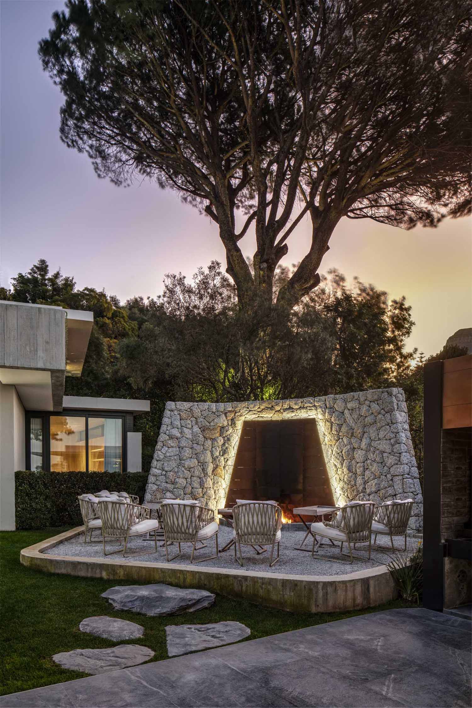 An outdoor fireplace with stone and steel backdrop and seating.