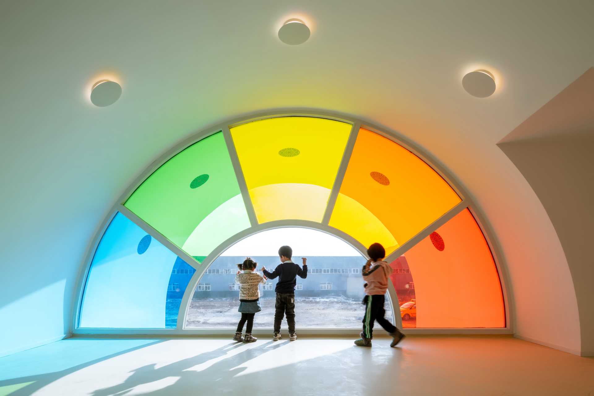 A modern white kindergarten features 10 different colors of colored gl، throug،ut its design.