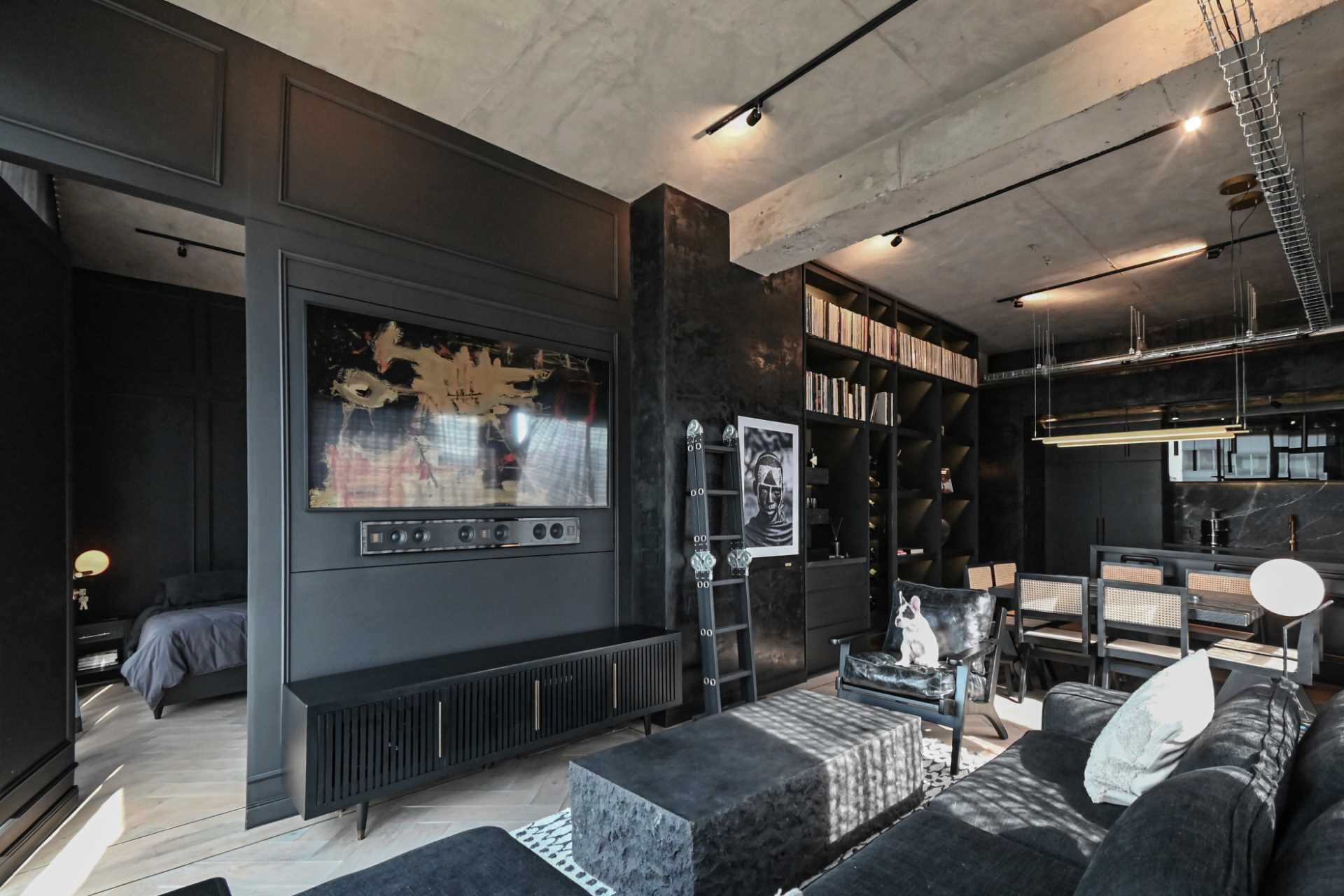 A modern black apartment interior with an open plan living room, dining area, and kitchen.