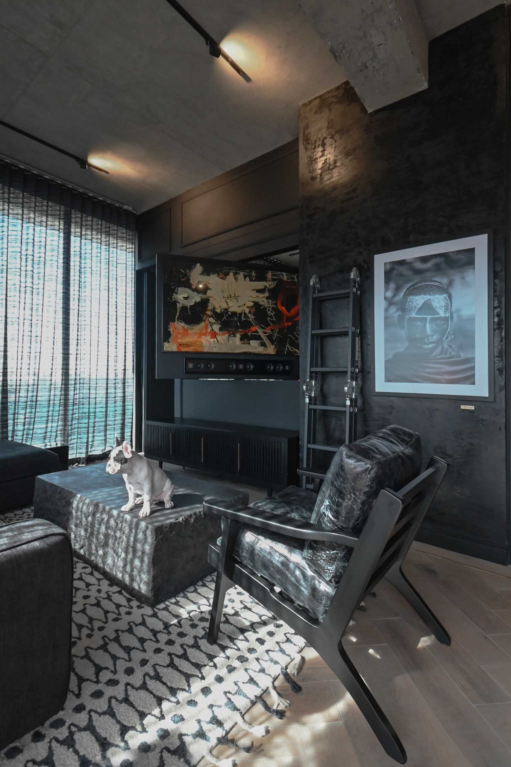 A modern black apartment interior with an open plan living room, dining area, and kitchen.