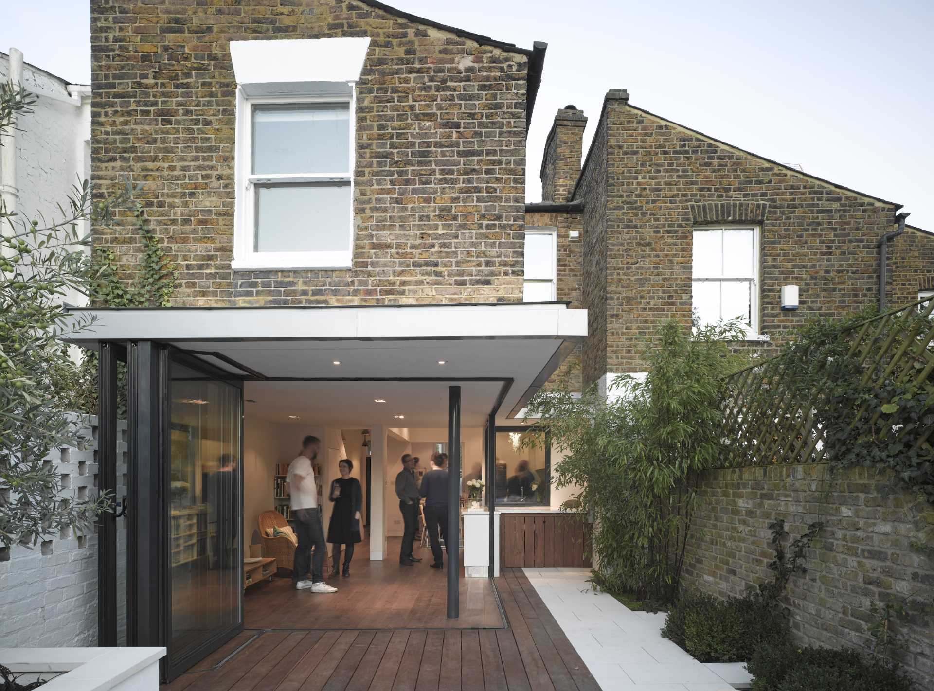 In this house renovation, the walls were replaced with glass doors that open the entire corner, creating a seamless indoor/outdoor experience.