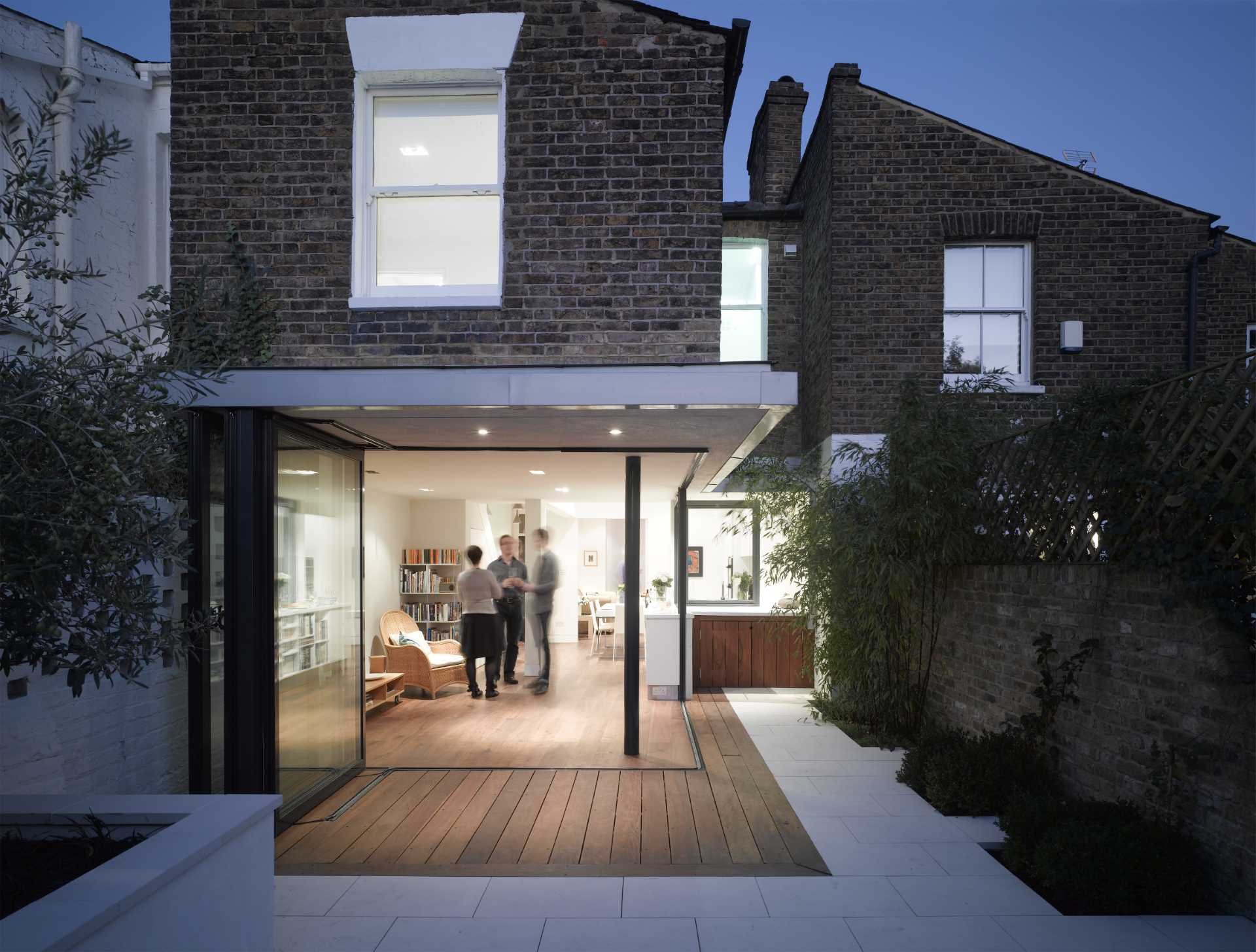 In this house renovation, the walls were replaced with glass doors that open the entire corner, creating a seamless indoor/outdoor experience.