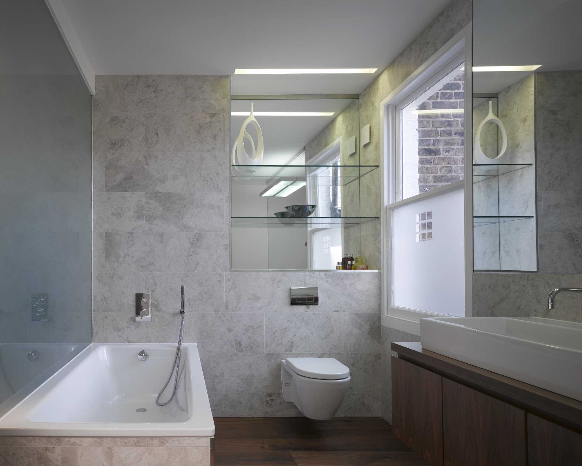 În această baie, pereții și podelele sunt acoperite cu gresie, în timp ce oglinzile reflectă lumina din jurul interiorului.