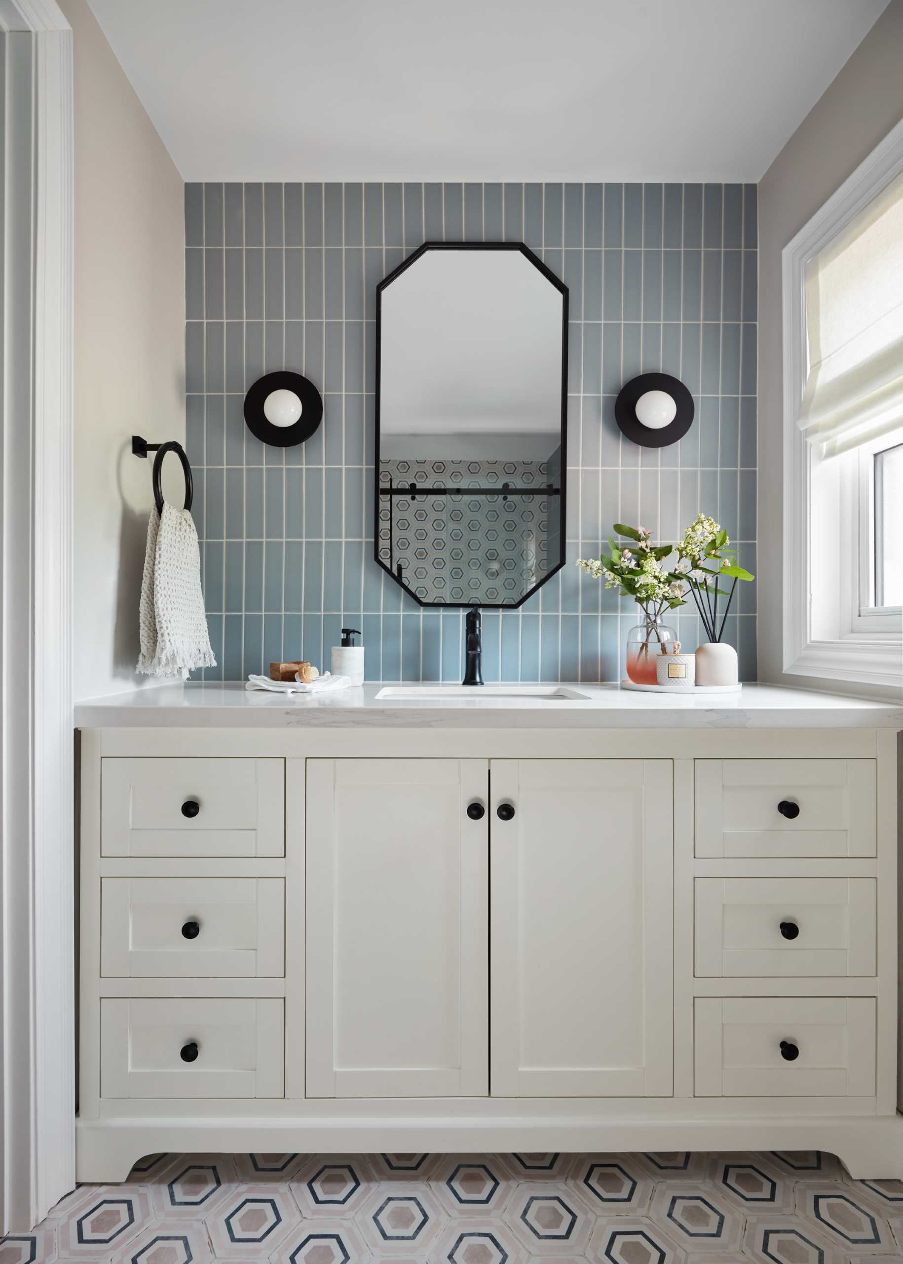 In this primary bathroom, blue-grey tiles line the wall, while patterned hexagonal tiles feature on the floor.