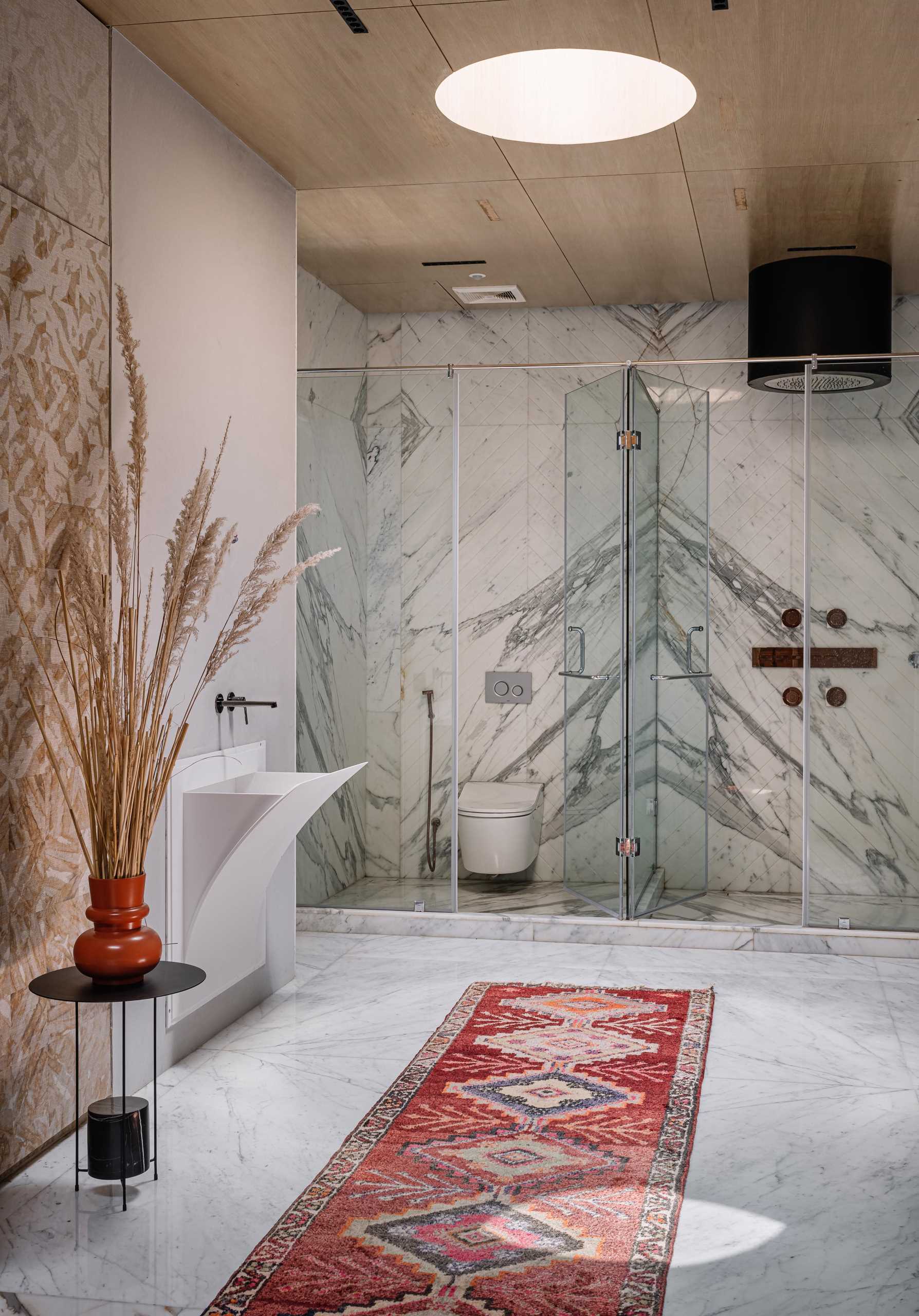 A modern bathroom with a skylight above the shower and toilet, both of which are enclosed behind glass