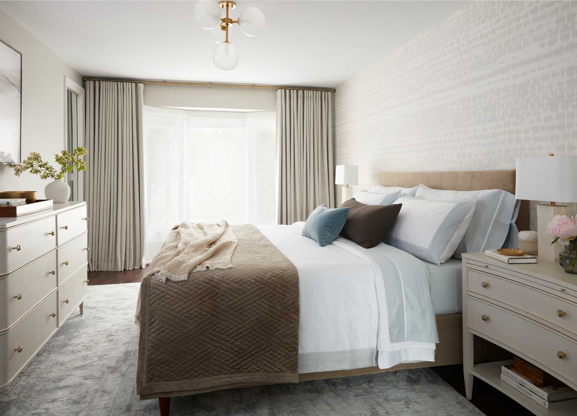 In the primary bedroom, contemporary furnishings make for a calm environment, while a closet with mirrored doors reflects light around the room.