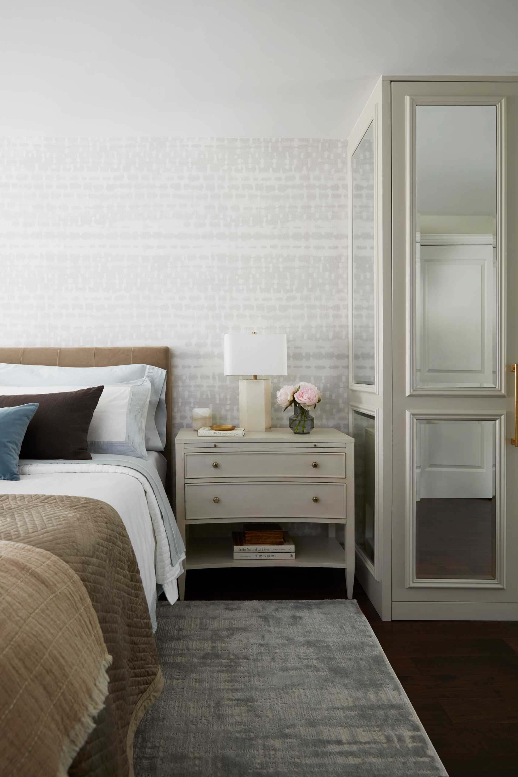 In the primary bedroom, contemporary furnishings make for a calm environment, while a closet with mirrored doors reflects light around the room.