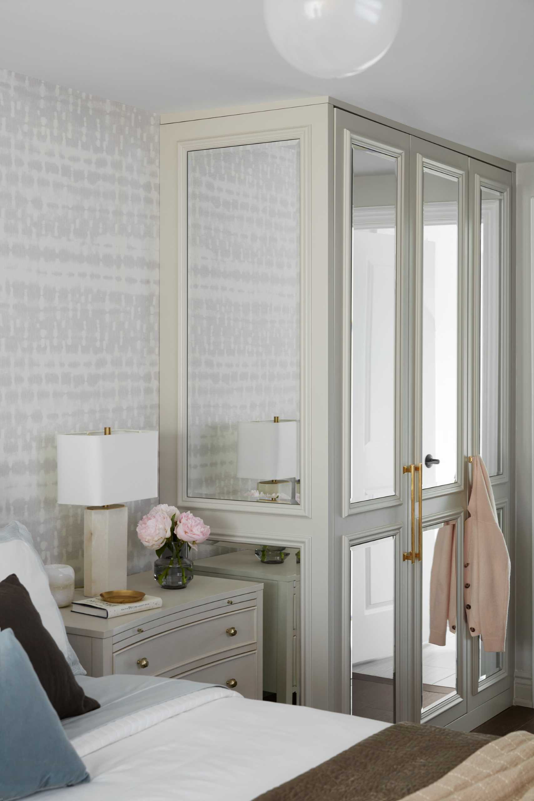 In the primary bedroom, contemporary furnishings make for a calm environment, while a closet with mirrored doors reflects light around the room.