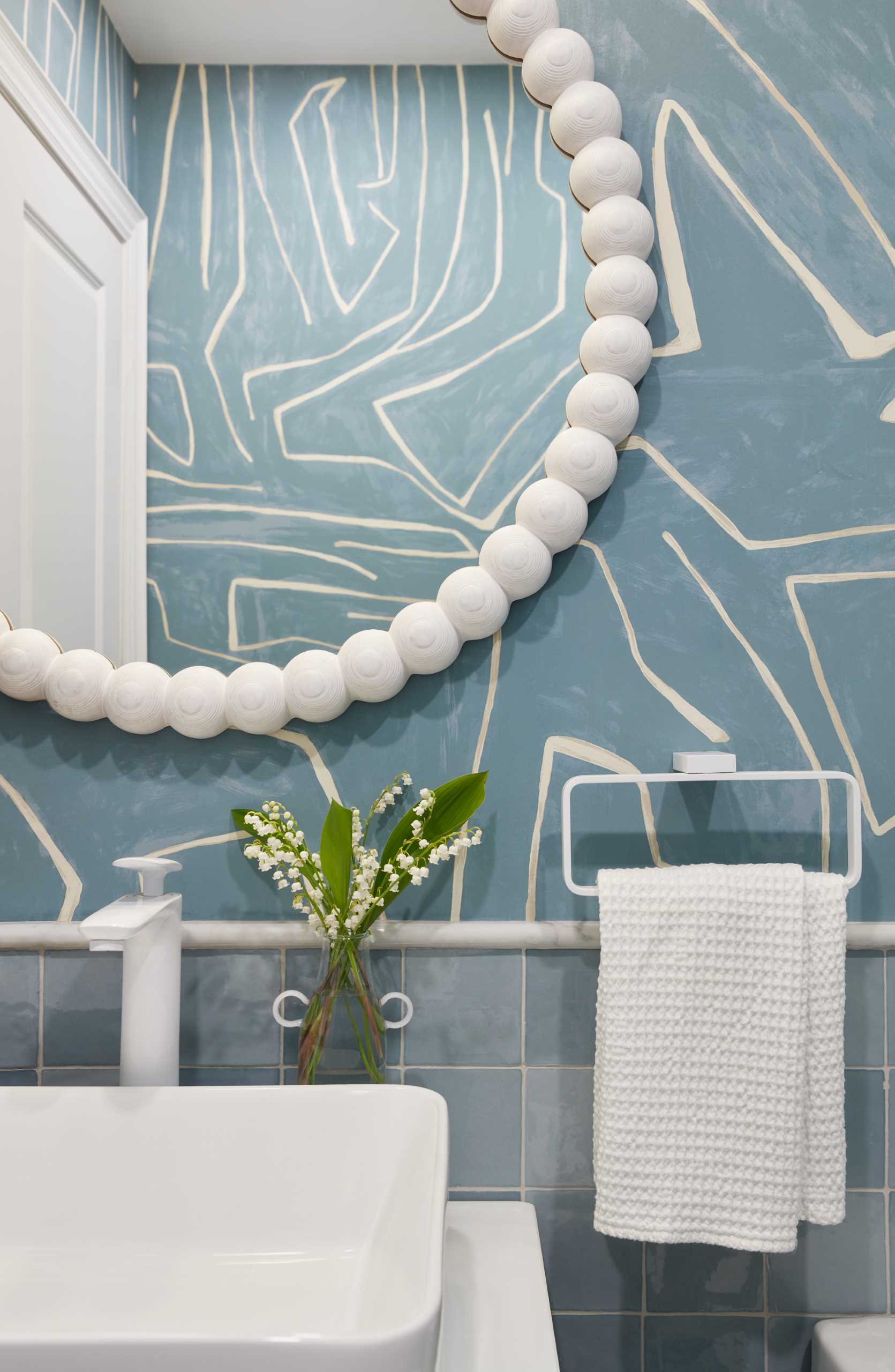 In this contemporary bathroom, graphic wallpaper covers the walls and the white accents help to keep the interior bright.