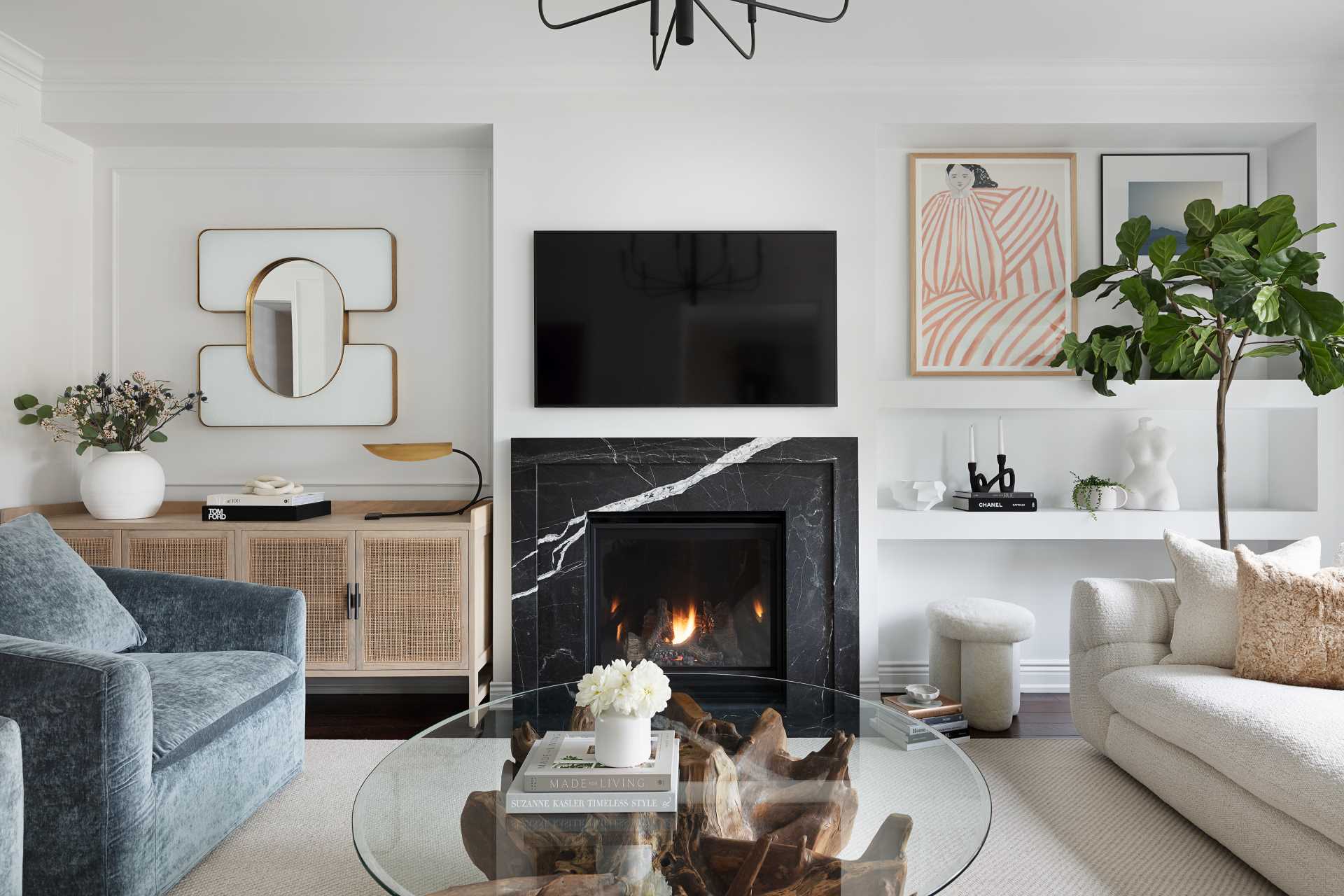 A living room that's casual in its design with a fireplace and TV, open shelving, and a wood cabinet with textured woven details.