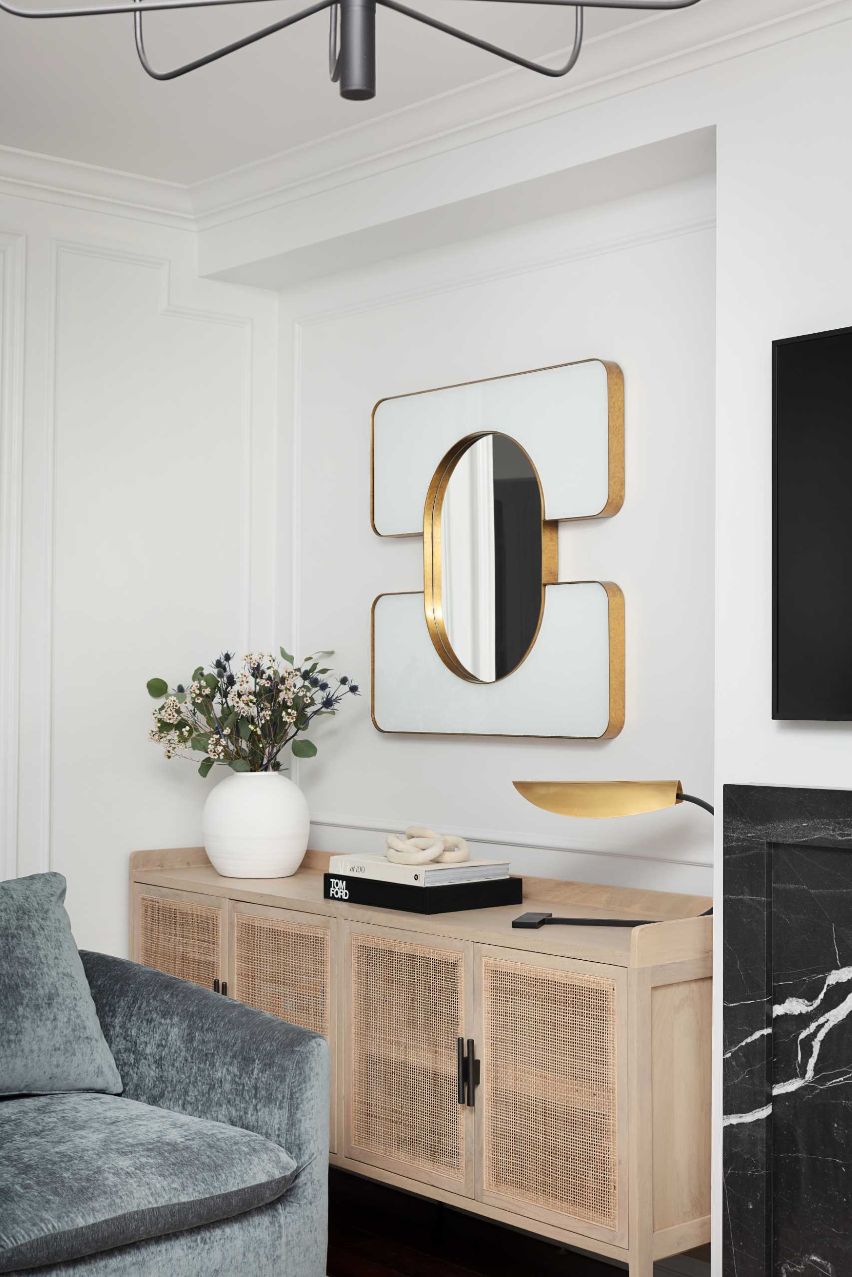 A living room that's casual in its design with a fireplace and TV, open shelving, and a wood cabinet with textured woven details.