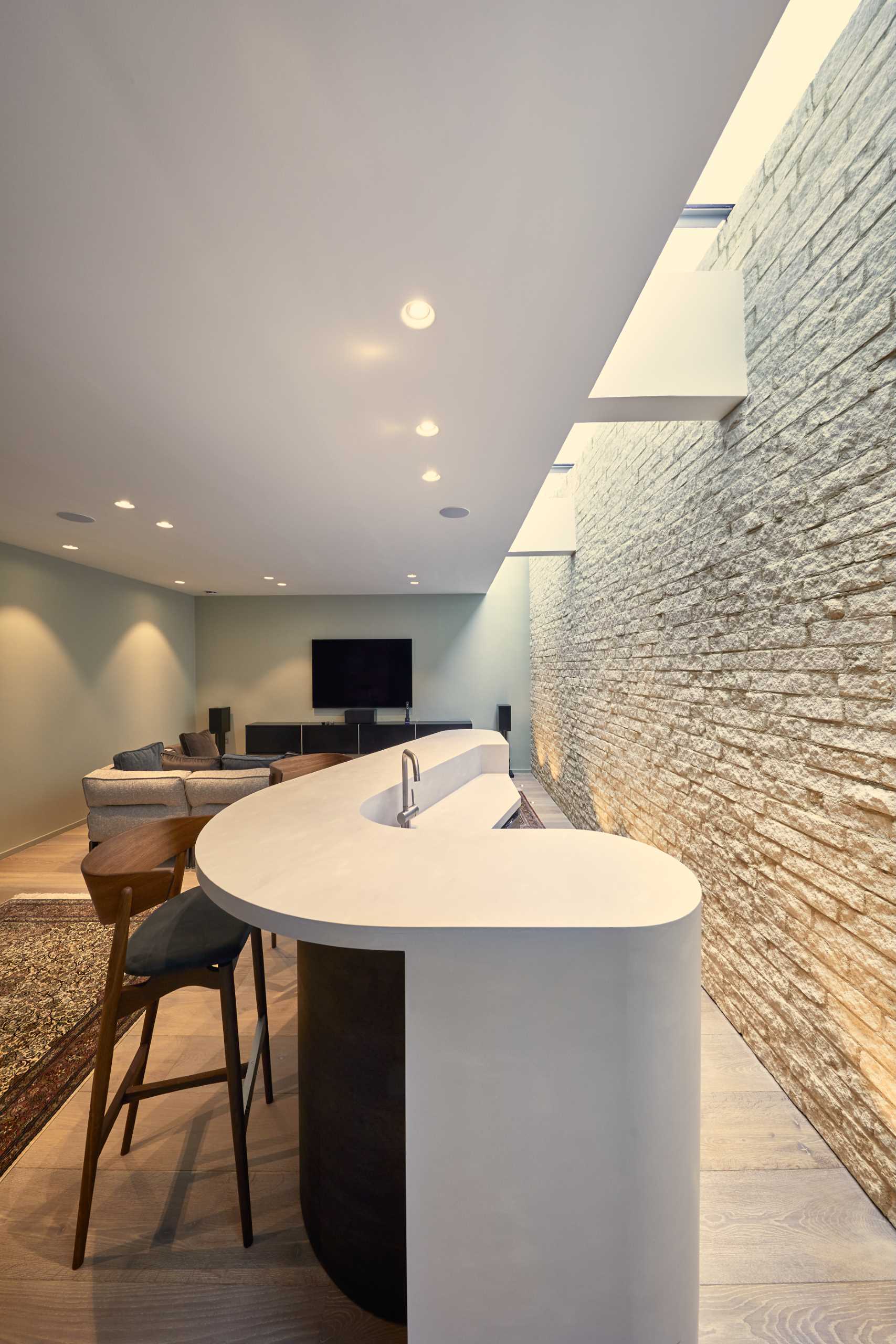 A modern home with a stone wall and a curved bar.