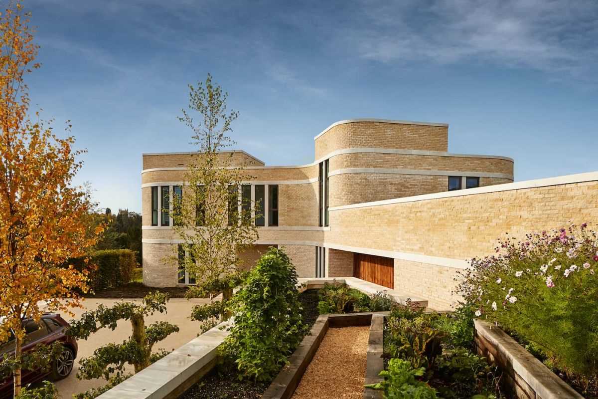 A modern stone home with ribbons of cast Portland stone snaking around the curved exterior.