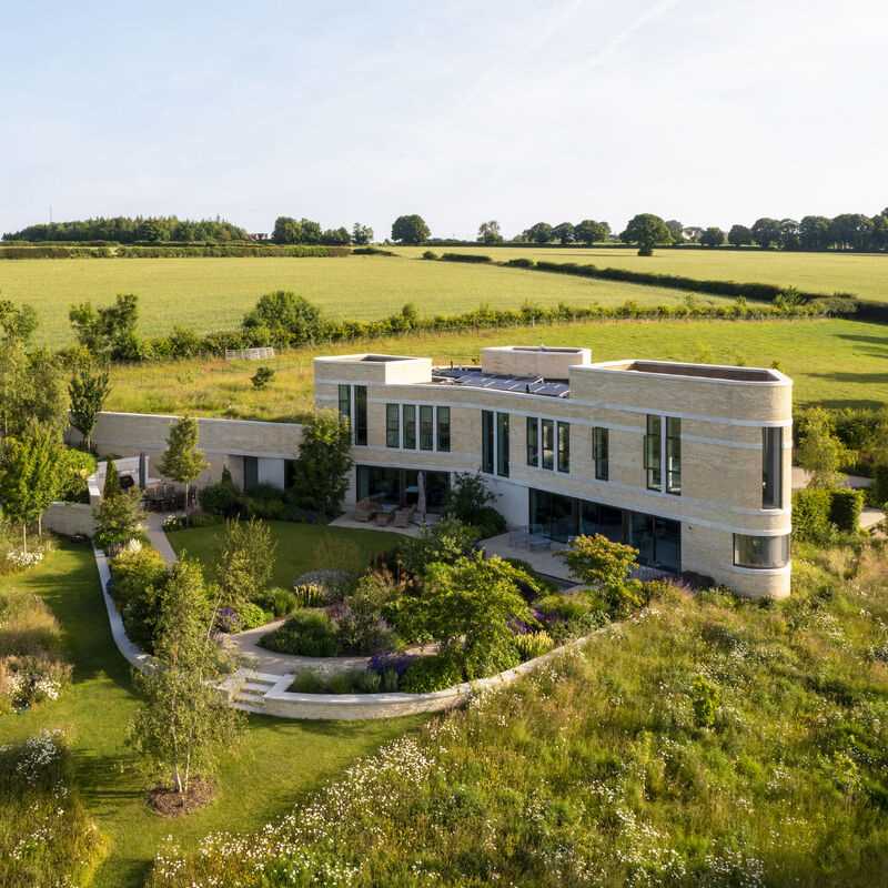 A modern stone home with ribbons of cast Portland stone snaking around the curved exterior.