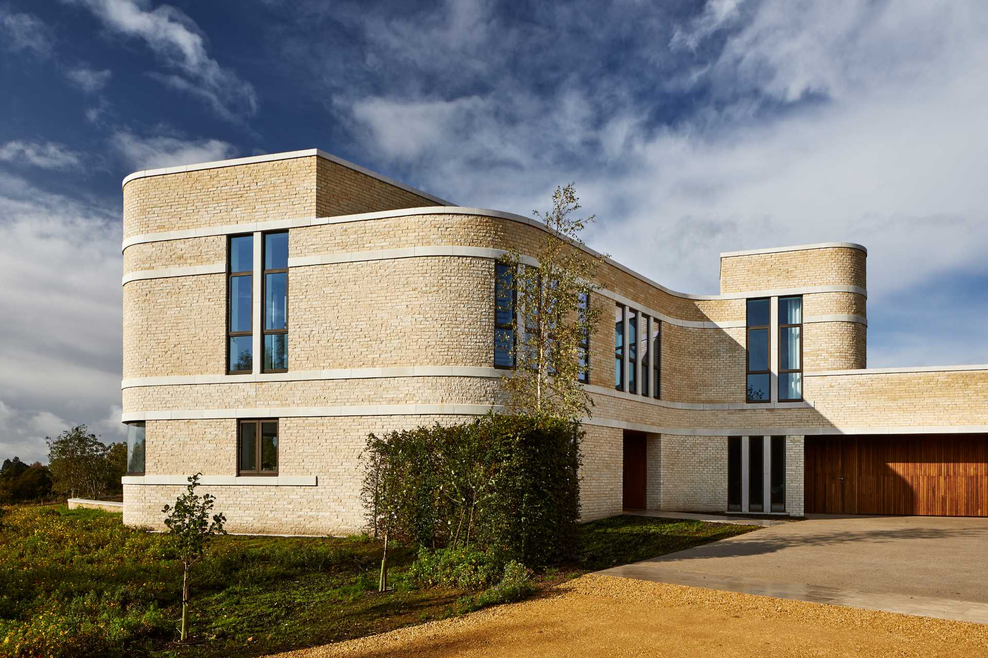 A modern stone home with ribbons of cast Portland stone snaking around the curved exterior.
