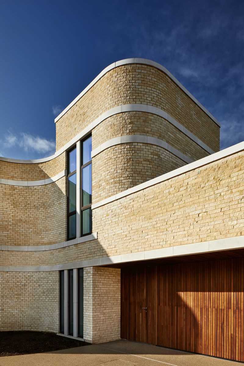 A modern stone home with ribbons of cast Portland stone snaking around the curved exterior.