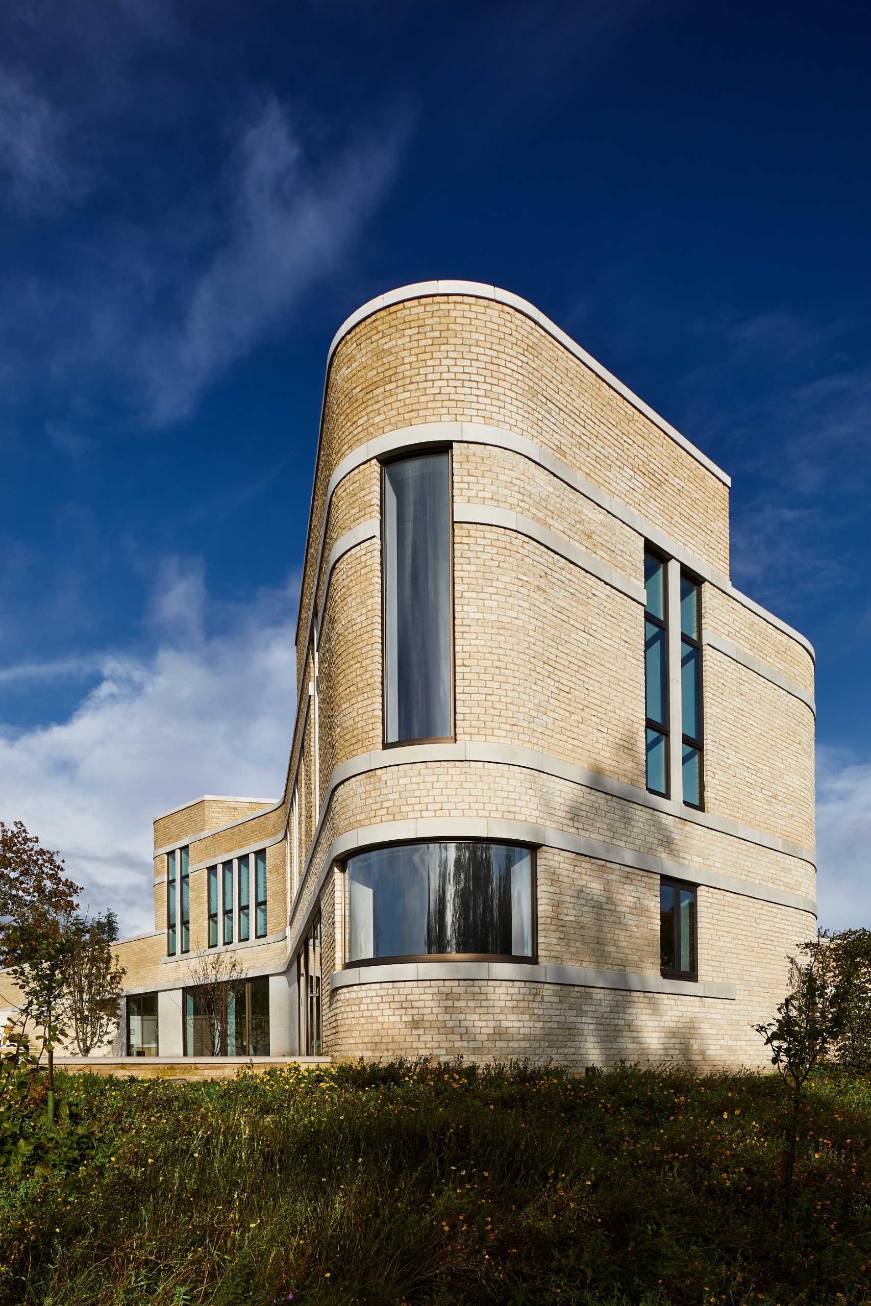 A modern stone home with ribbons of cast Portland stone snaking around the curved exterior.