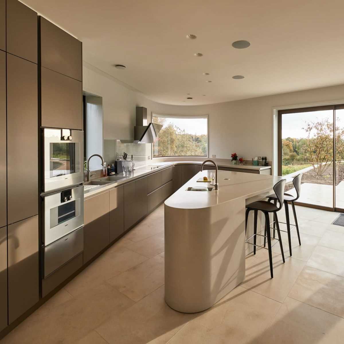 A modern kitchen with curved that reflect the design of the home.