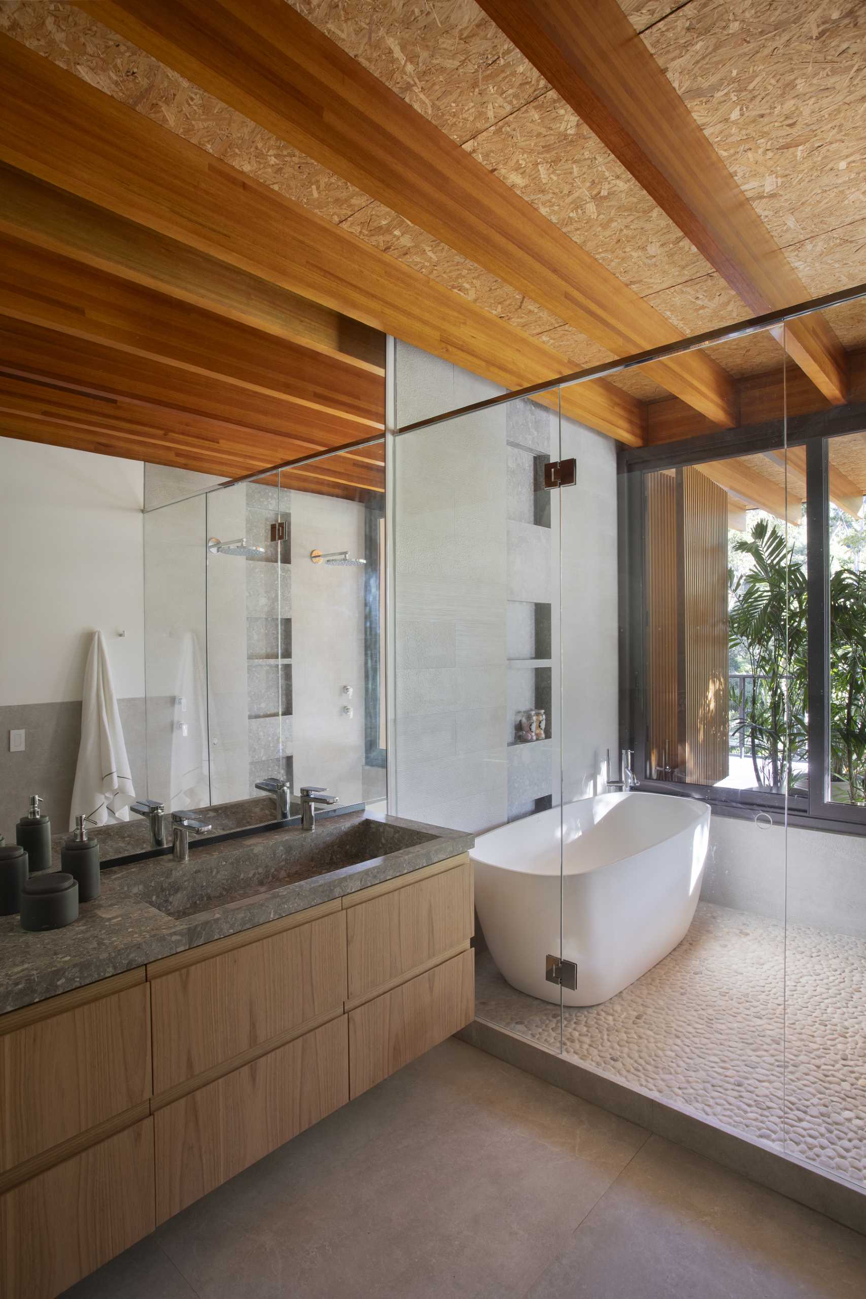 In this modern bathroom, there's a wet room that includes a freestanding bathtub, shower, and shelving niches.
