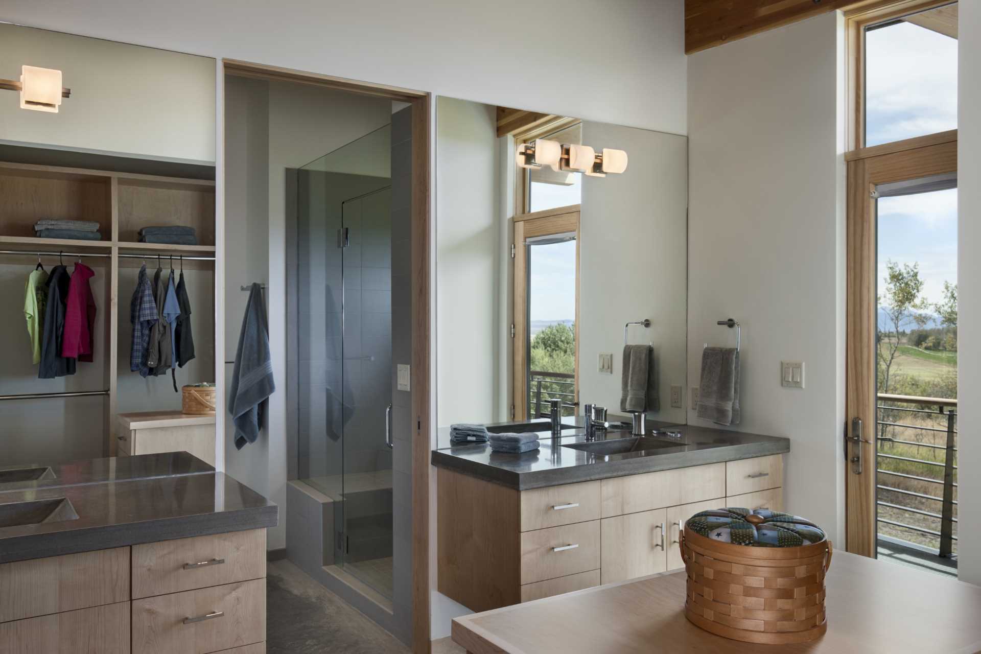 In this bathroom, dual vanities and a custom closet provide ample storage, while the shower is located through a doorway.