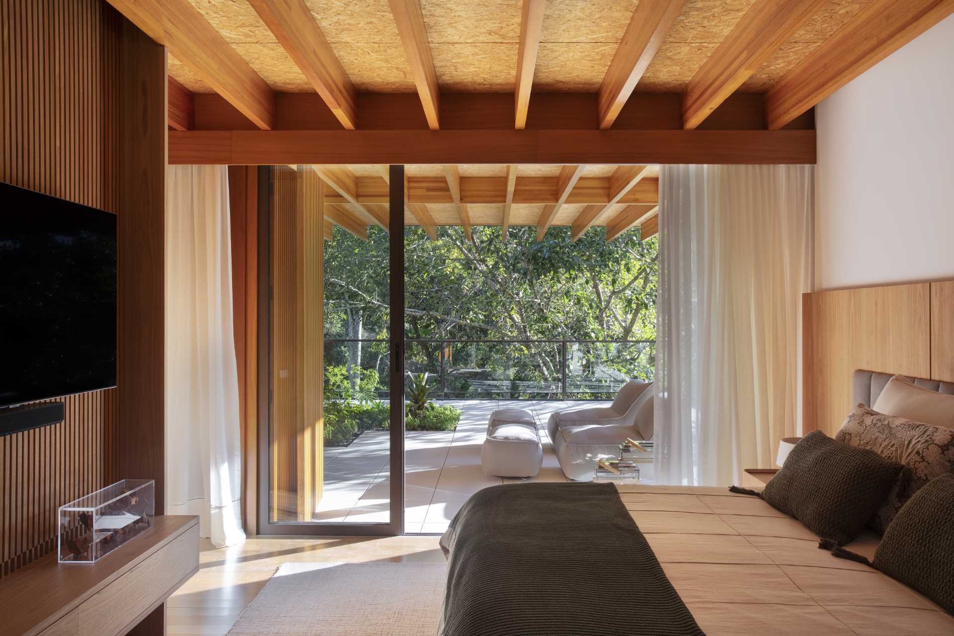 In this modern bedrooms, a sliding glass door opens the room to a balcony that's covered by the overhanging roof.