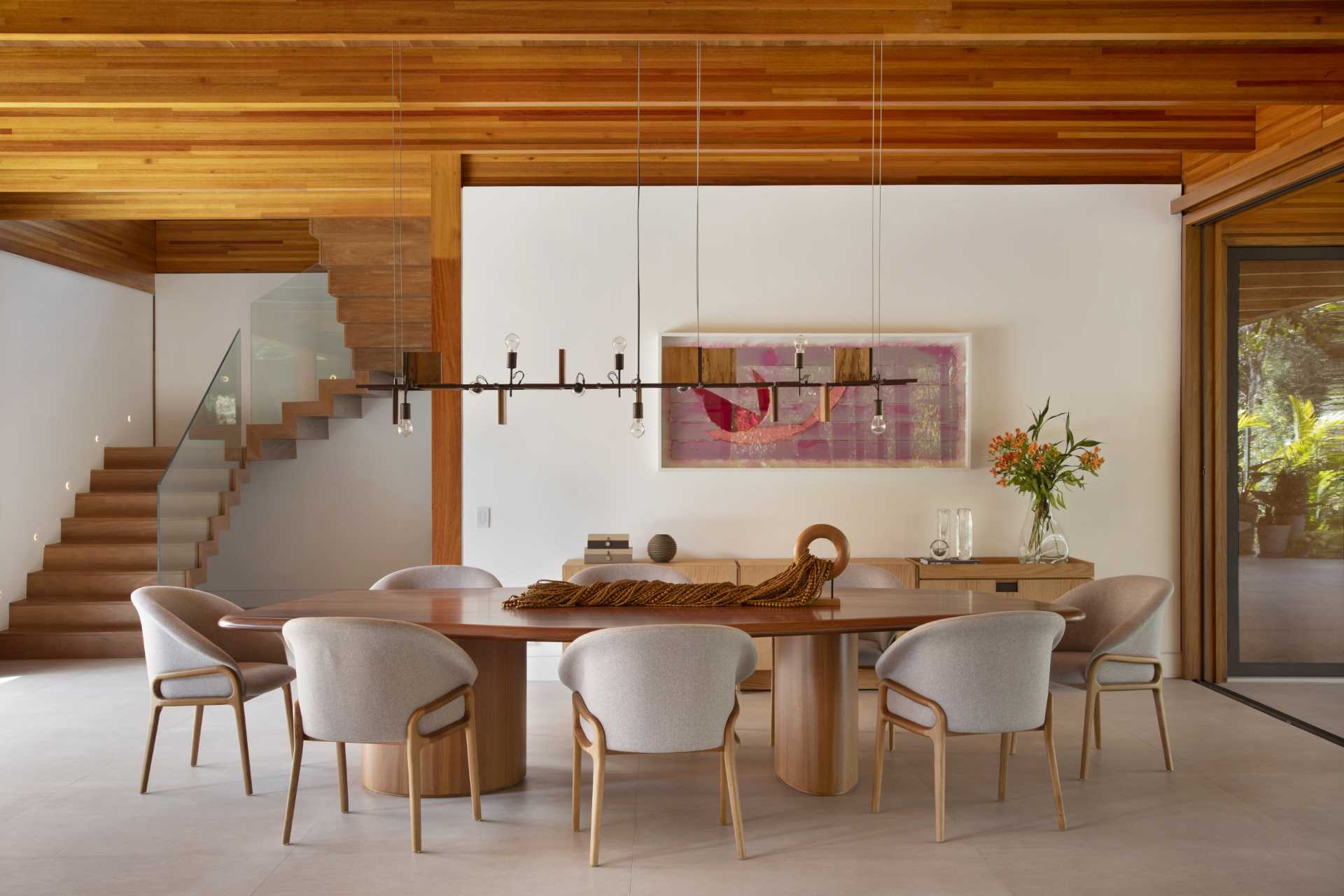 A modern dining room furnished with a wood table, while the floor is an Italian porcelain tile in a large format with a sandy tone.