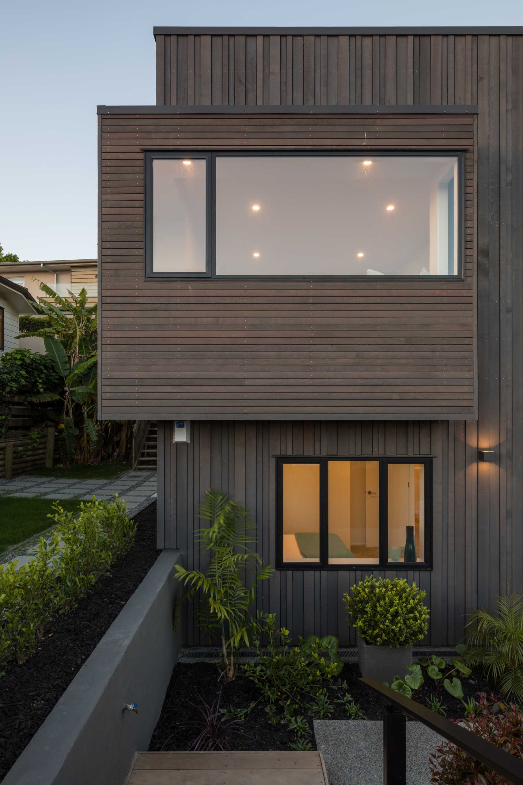 The exterior of this renovated home, which is clad in dark wood in both horizontal and vertical directions, also features black window frames.