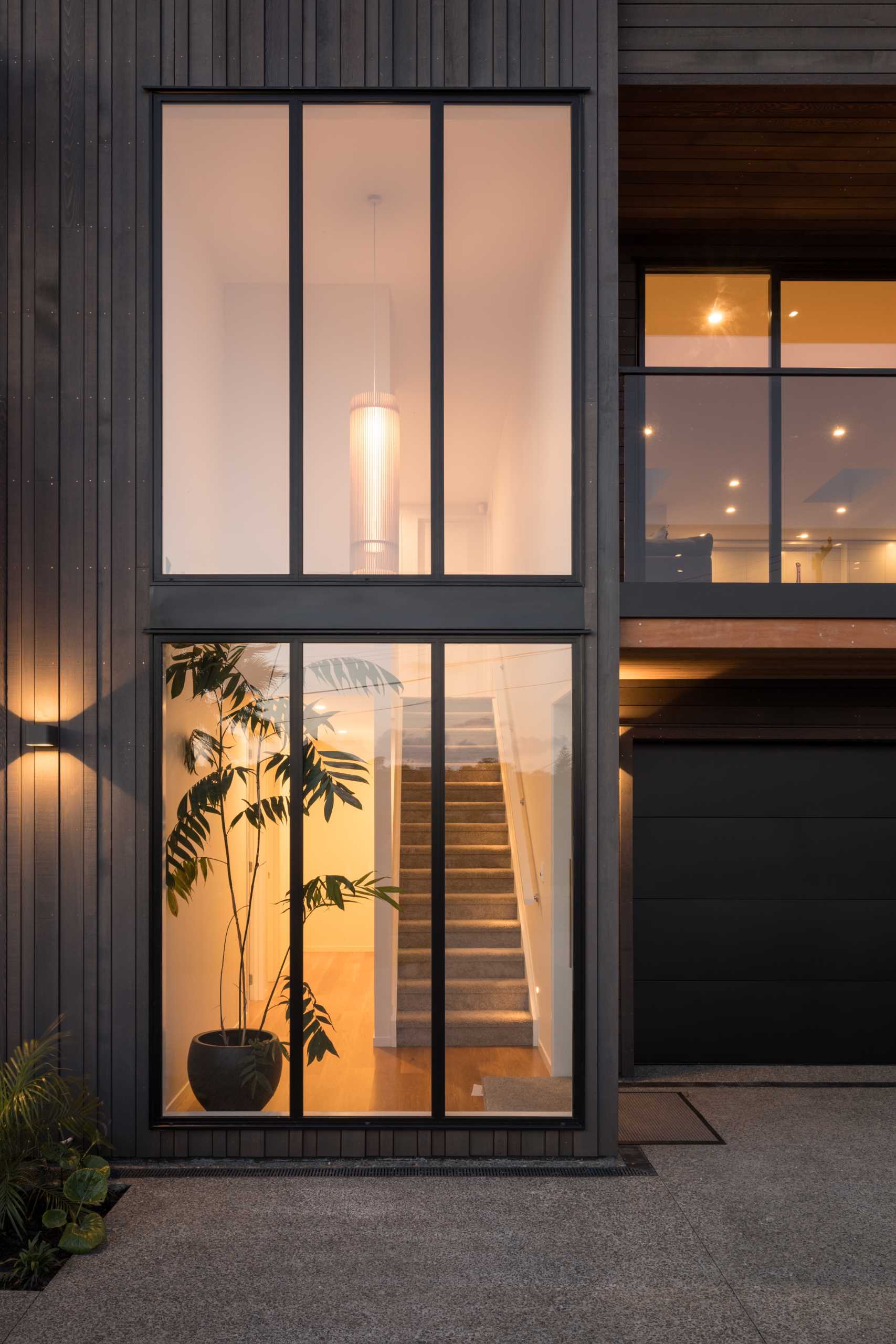 Tall windows allow the natural light to shine through to the interior of this renovated home, while in the evening, glimpses of the interior as well as the glow from the lights can be seen.