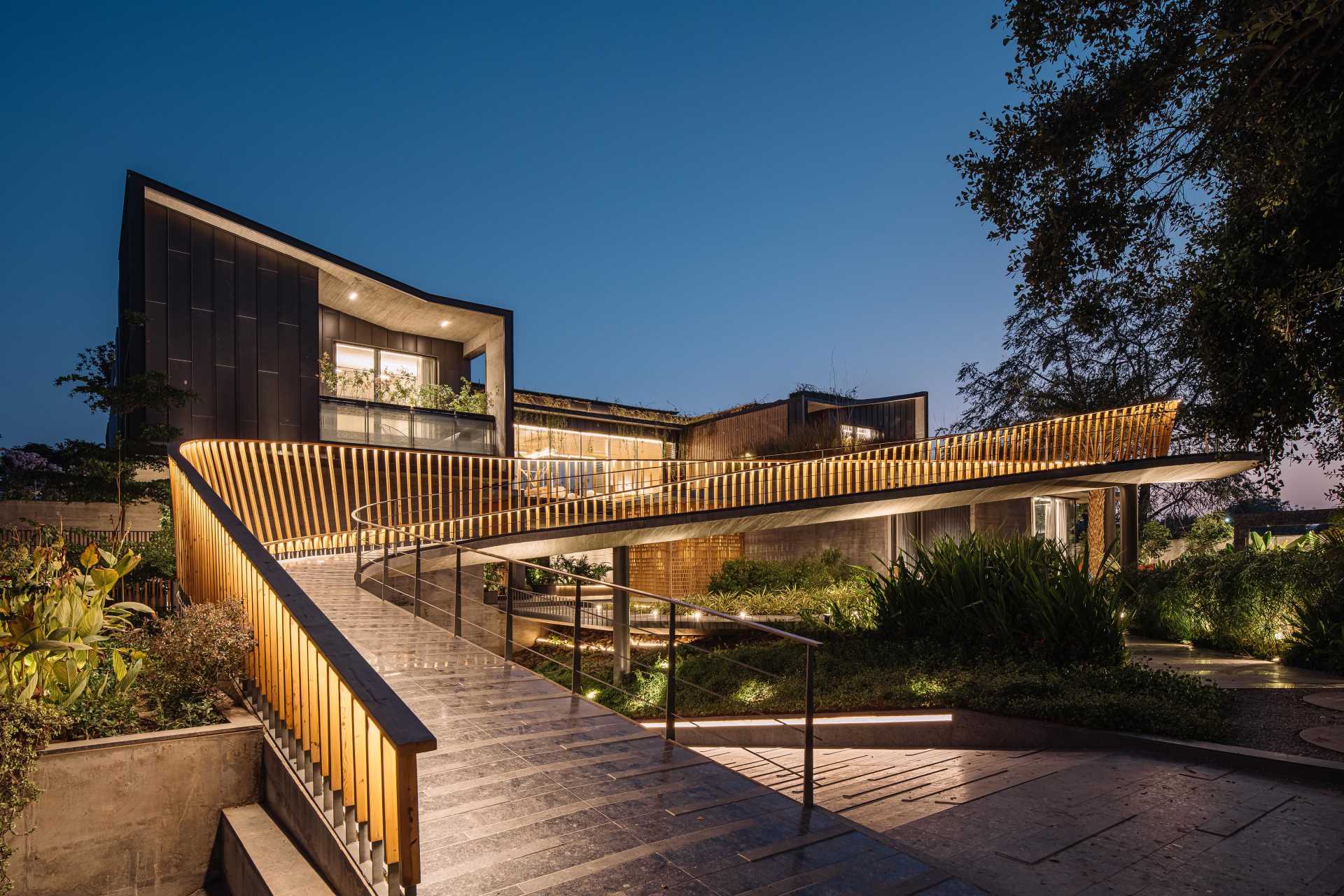 A curving bridge walkway leads to various outdoor entertaining areas of this modern home designed for multi-generational living.