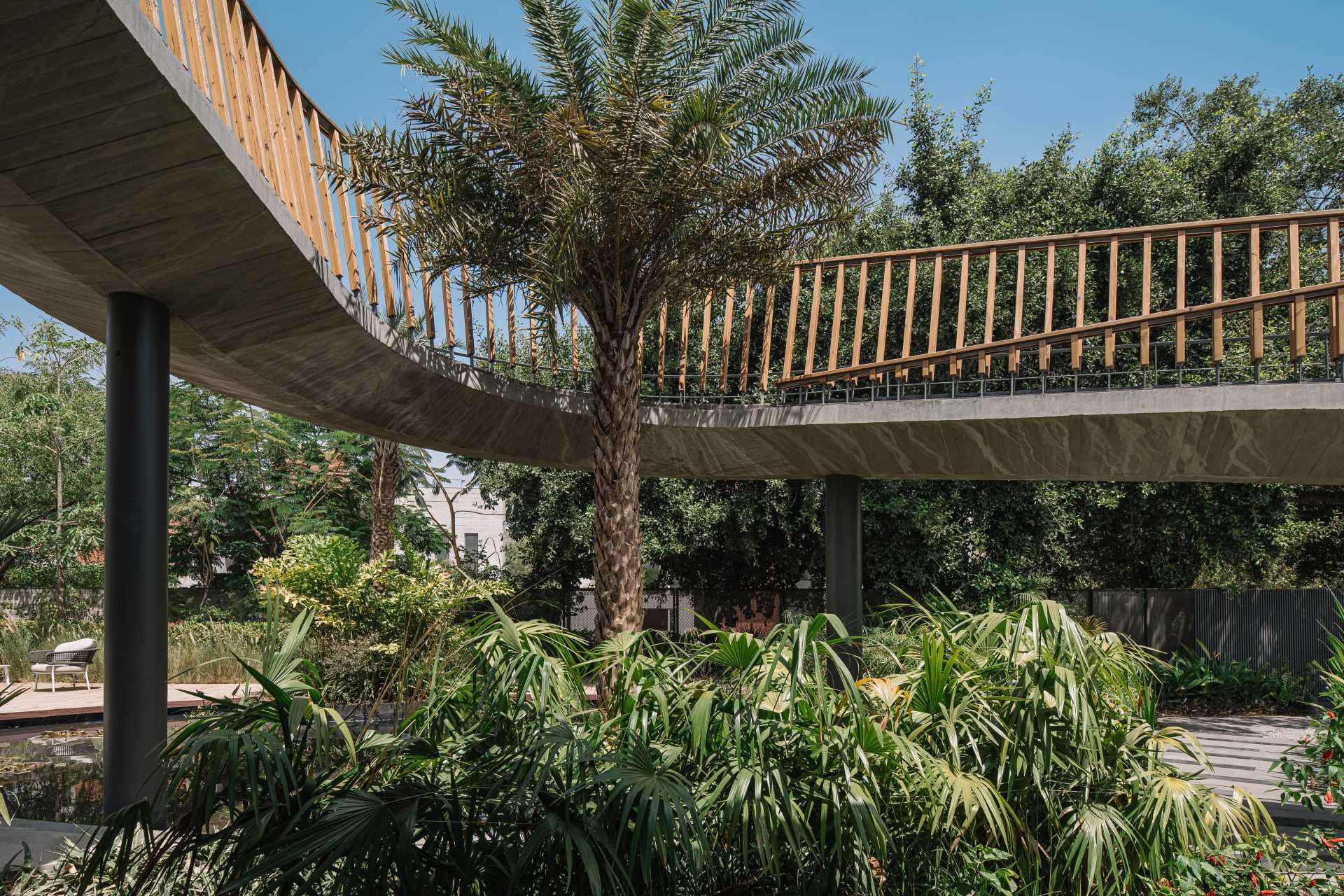 A curving bridge walkway leads to various outdoor entertaining areas of this modern home designed for multi-generational living.