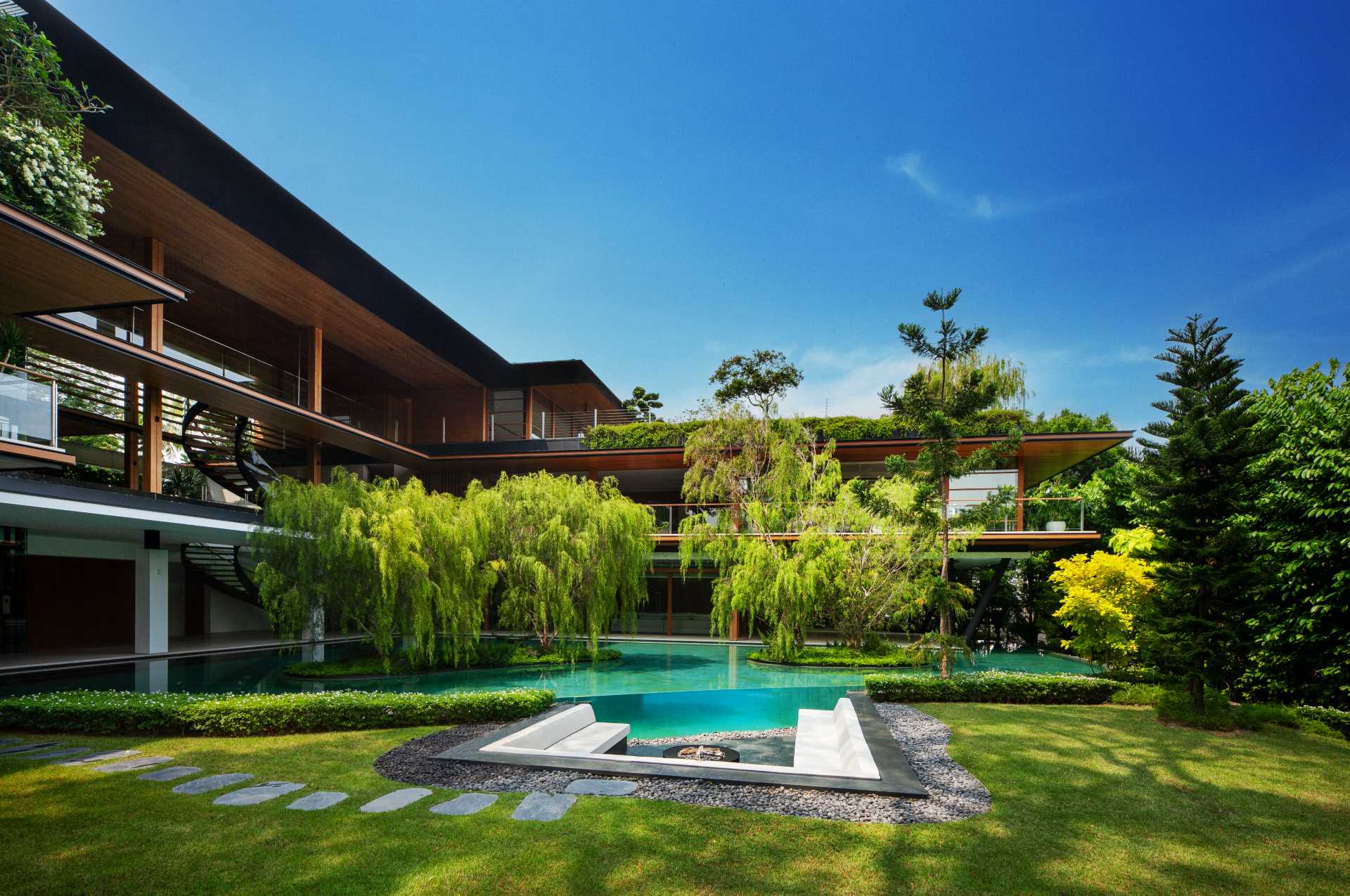 A modern house with plenty of greenery and water features that help keep the home cool.