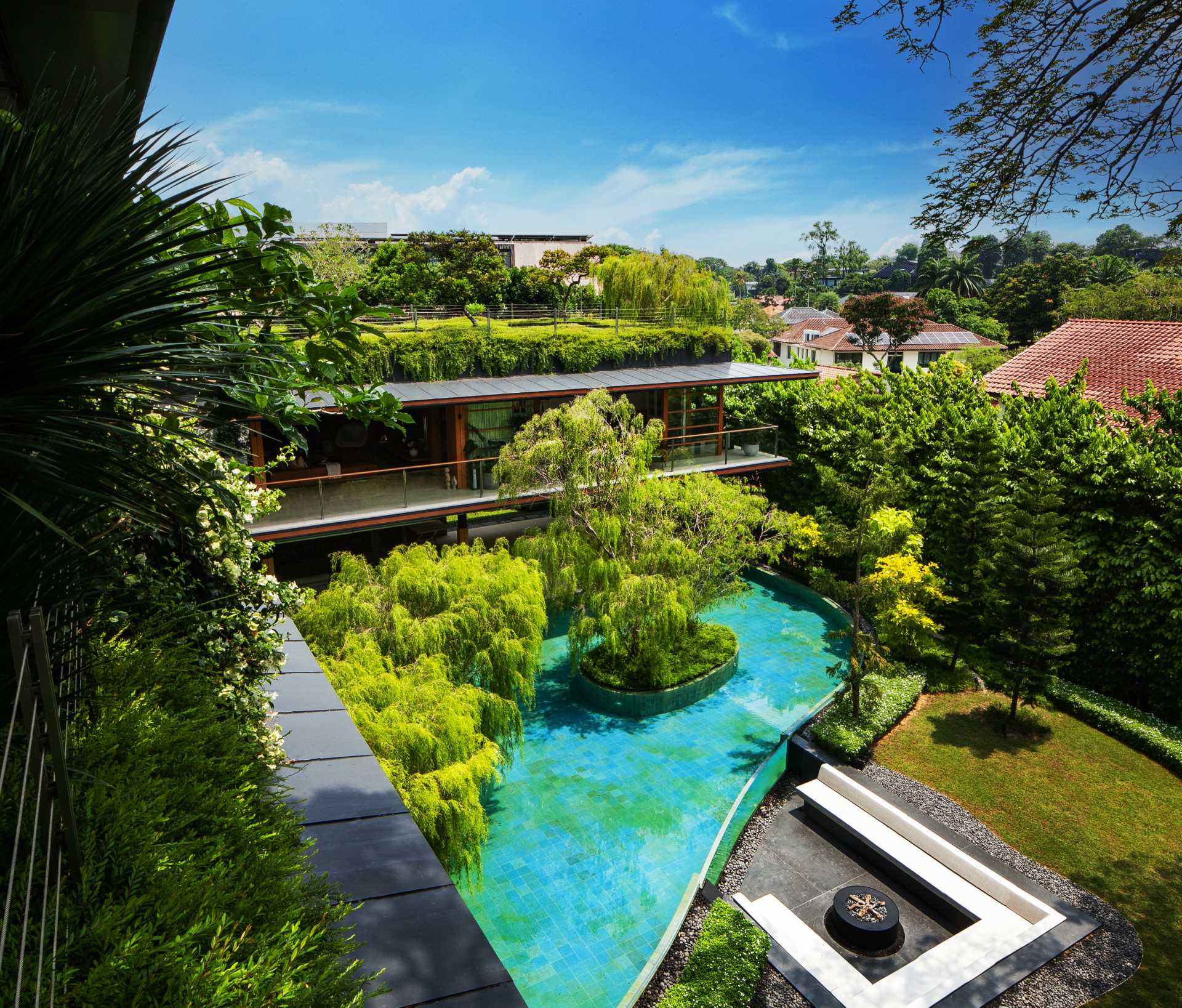 A modern house with plenty of greenery and water features that help keep the home cool.