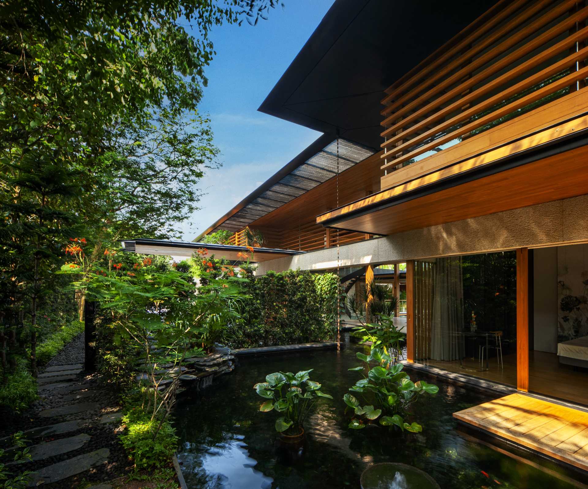 A modern house with plenty of greenery and water features that help keep the home cool.