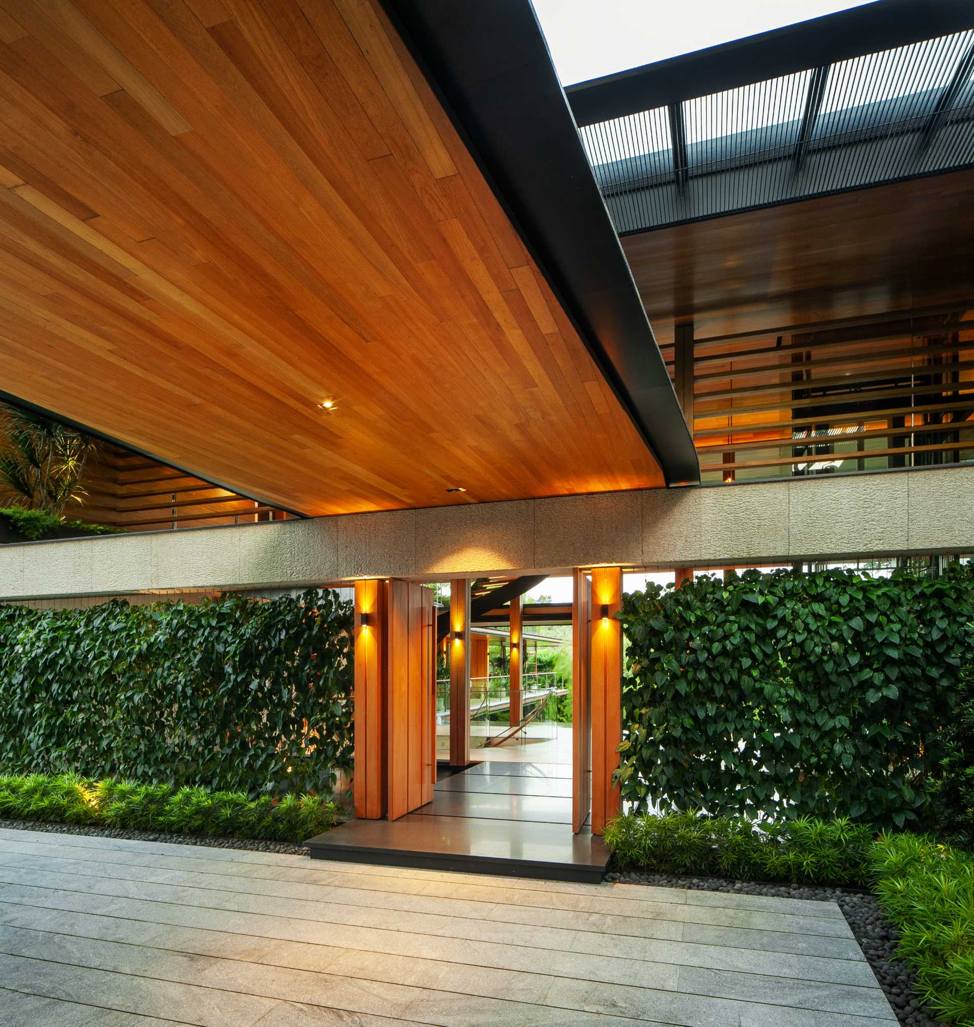 O casă modernă cu multă verdeață și caracteristici de apă care ajută la păstrarea răcoroasă a locuinței.