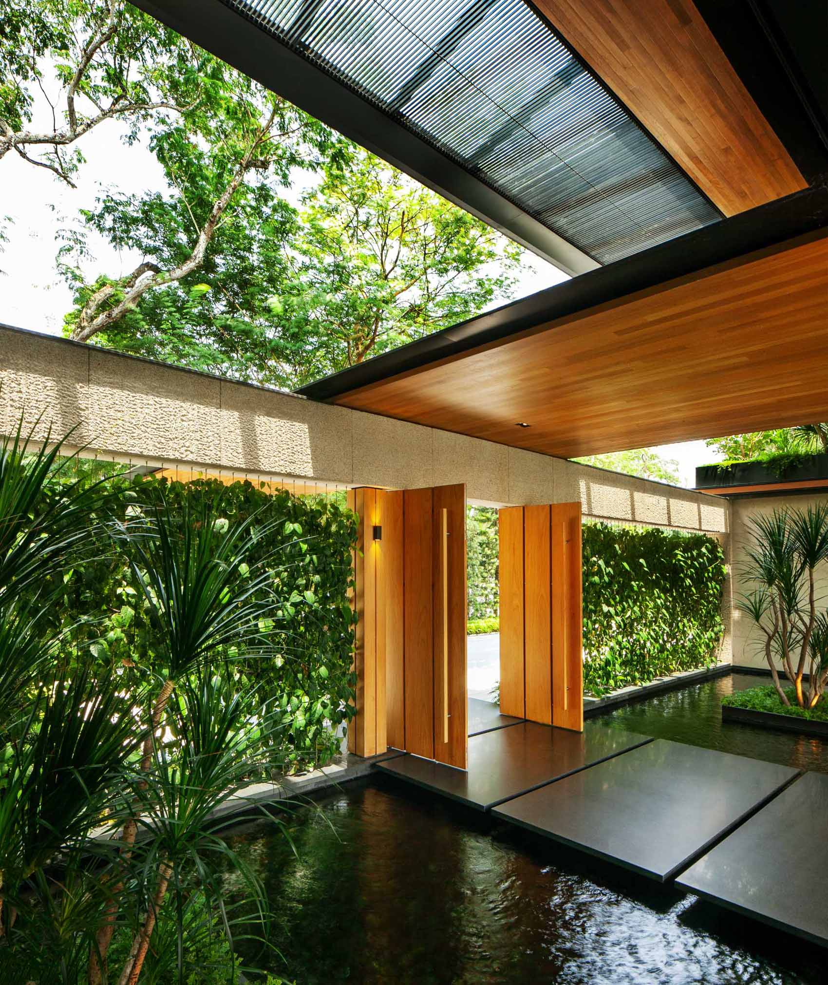 O casă modernă cu multă verdeață și caracteristici de apă care ajută la păstrarea răcoroasă a locuinței.