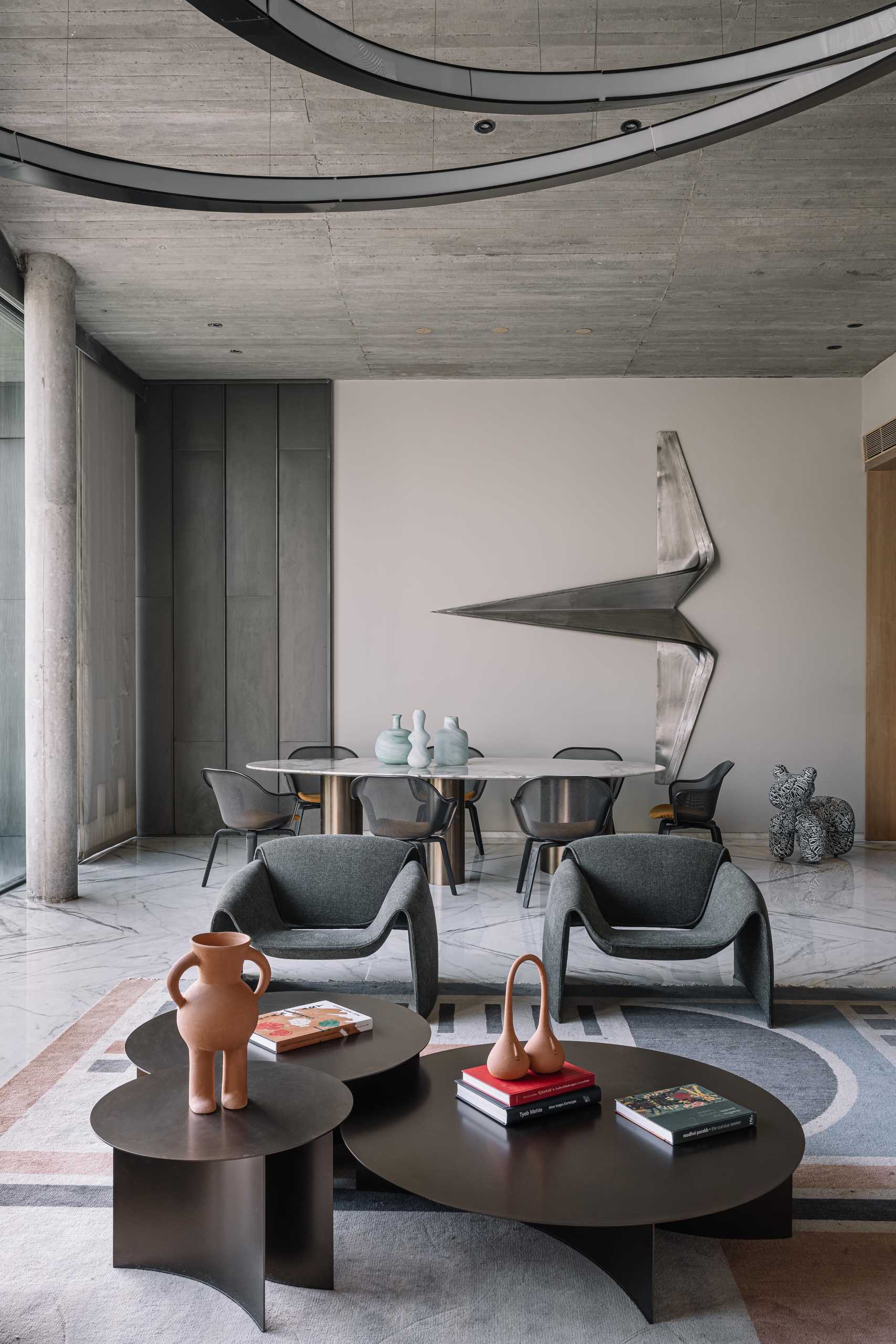 A modern dining room with a high ceiling and a metal sculpture on the wall.