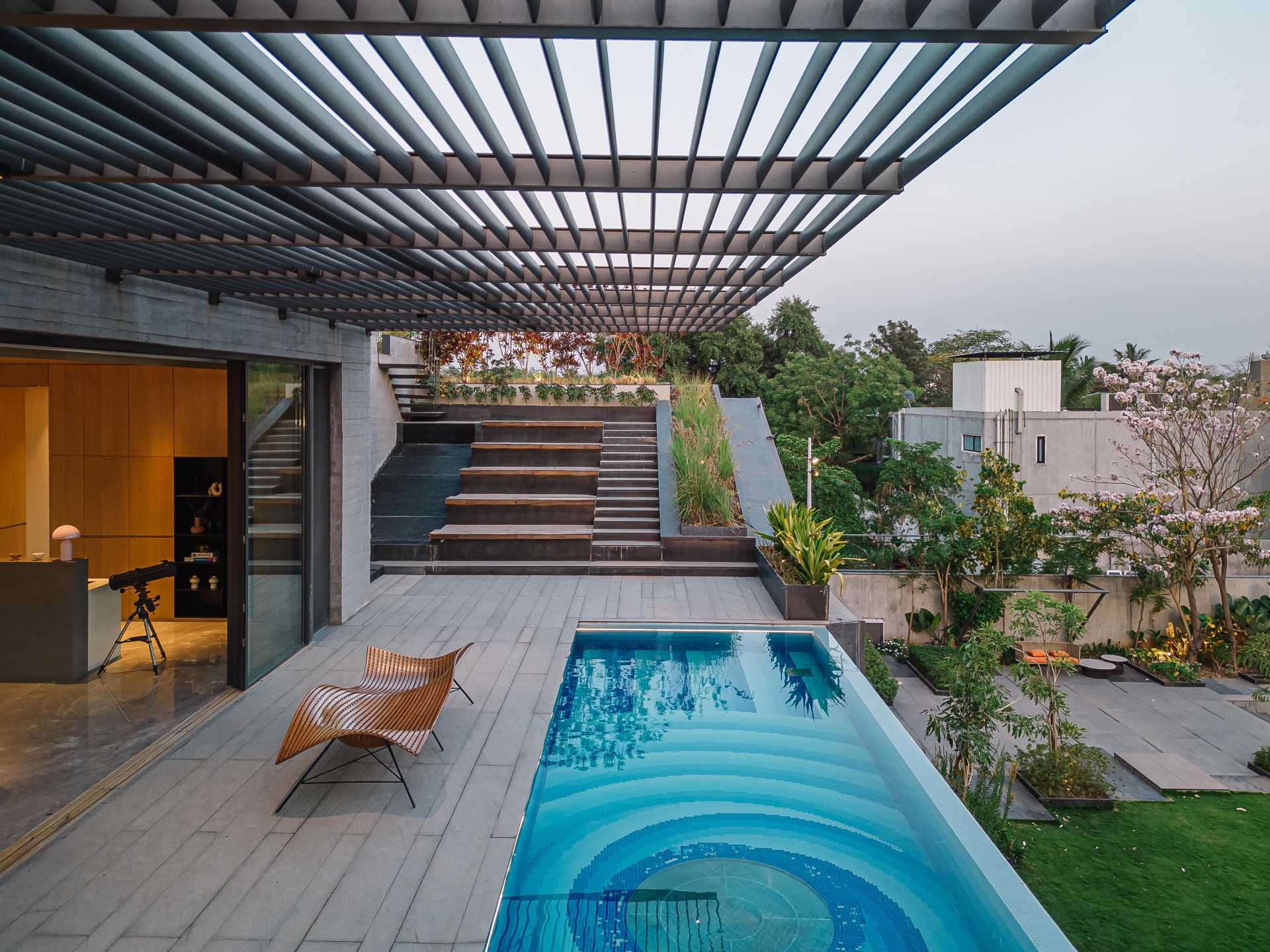 A decorative pattern of various blue shades lines the bottom of the pool, while the center of the pool has a window that shows the covered outdoor space below. 